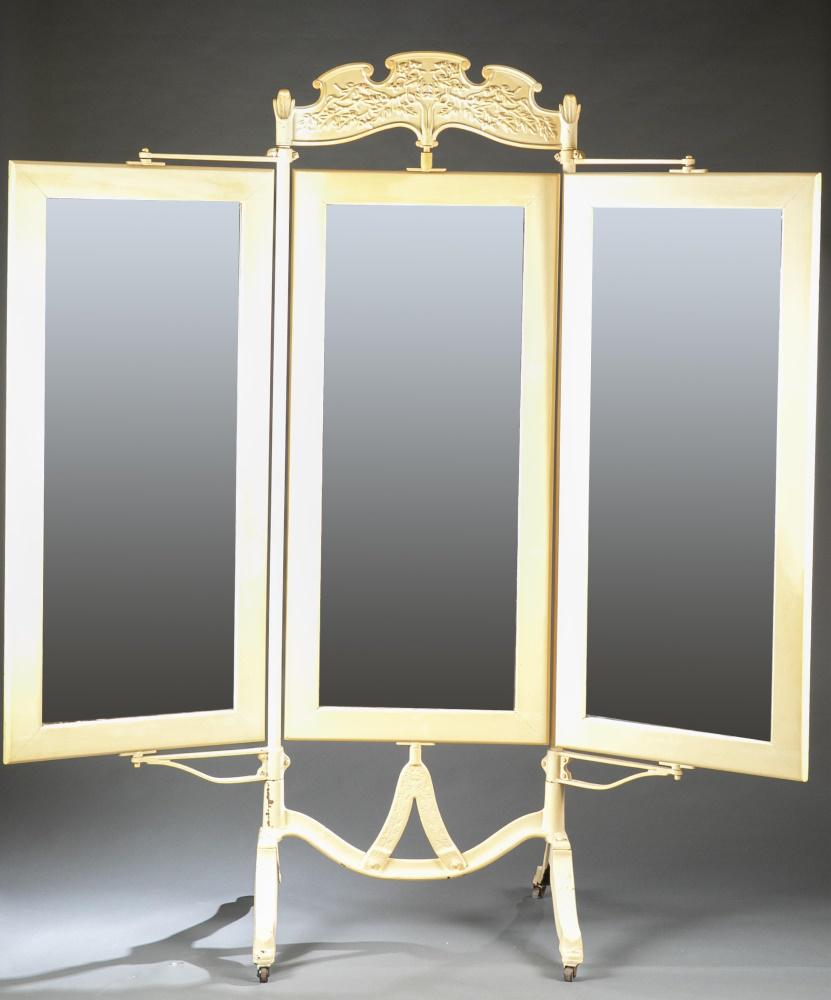 Tri-fold tailor's mirror.: An articulating tri-fold tailor's mirror on iron casters.19th century. Painted iron housing and base, mirrors have painted wood frame and backing. Impressed floral motif on casters and raised floral m