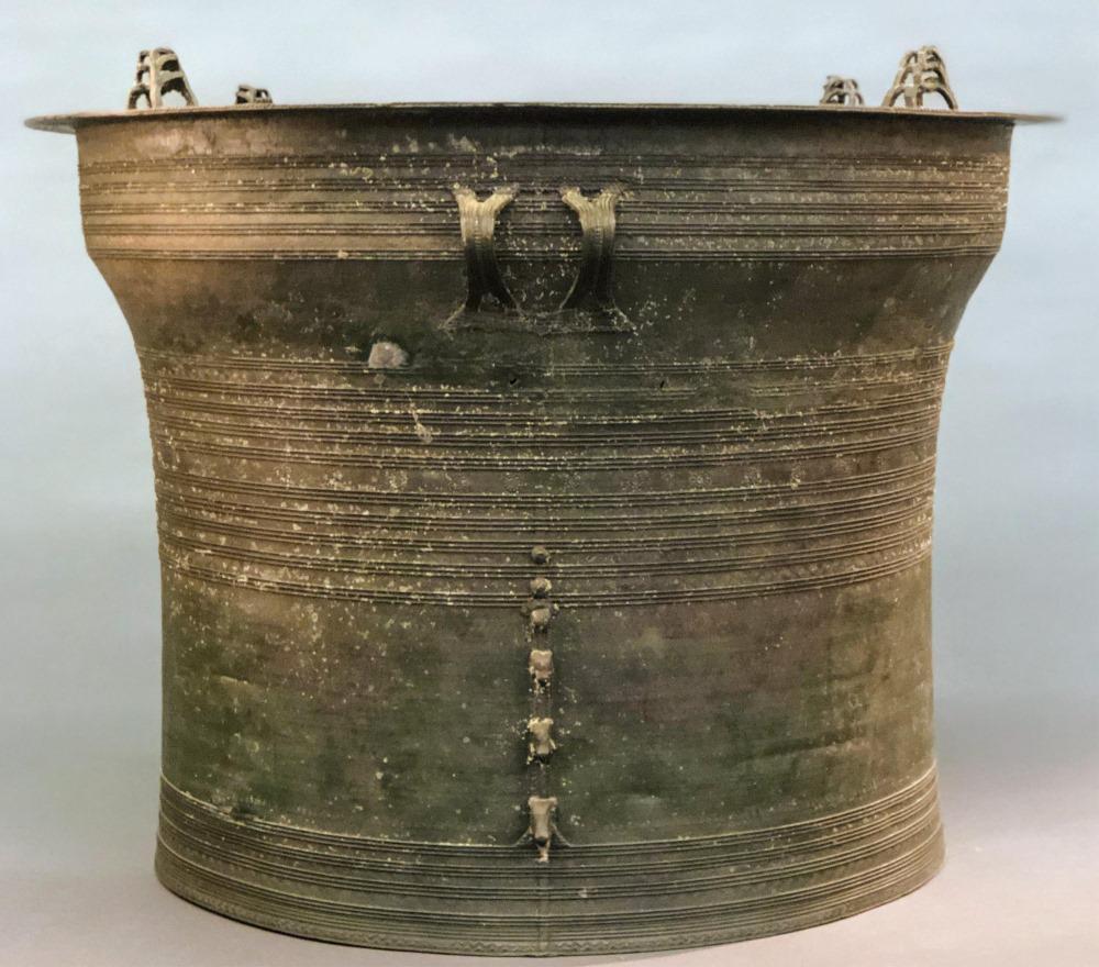 Southeast Asian bronze rain drum.: A bronze Southeast Asian rain drum. Corseted bronze form with incised concentric rings and star pattern on top. Four triple-stacked frog form finials on top edge of drum and double-handle loops on sid