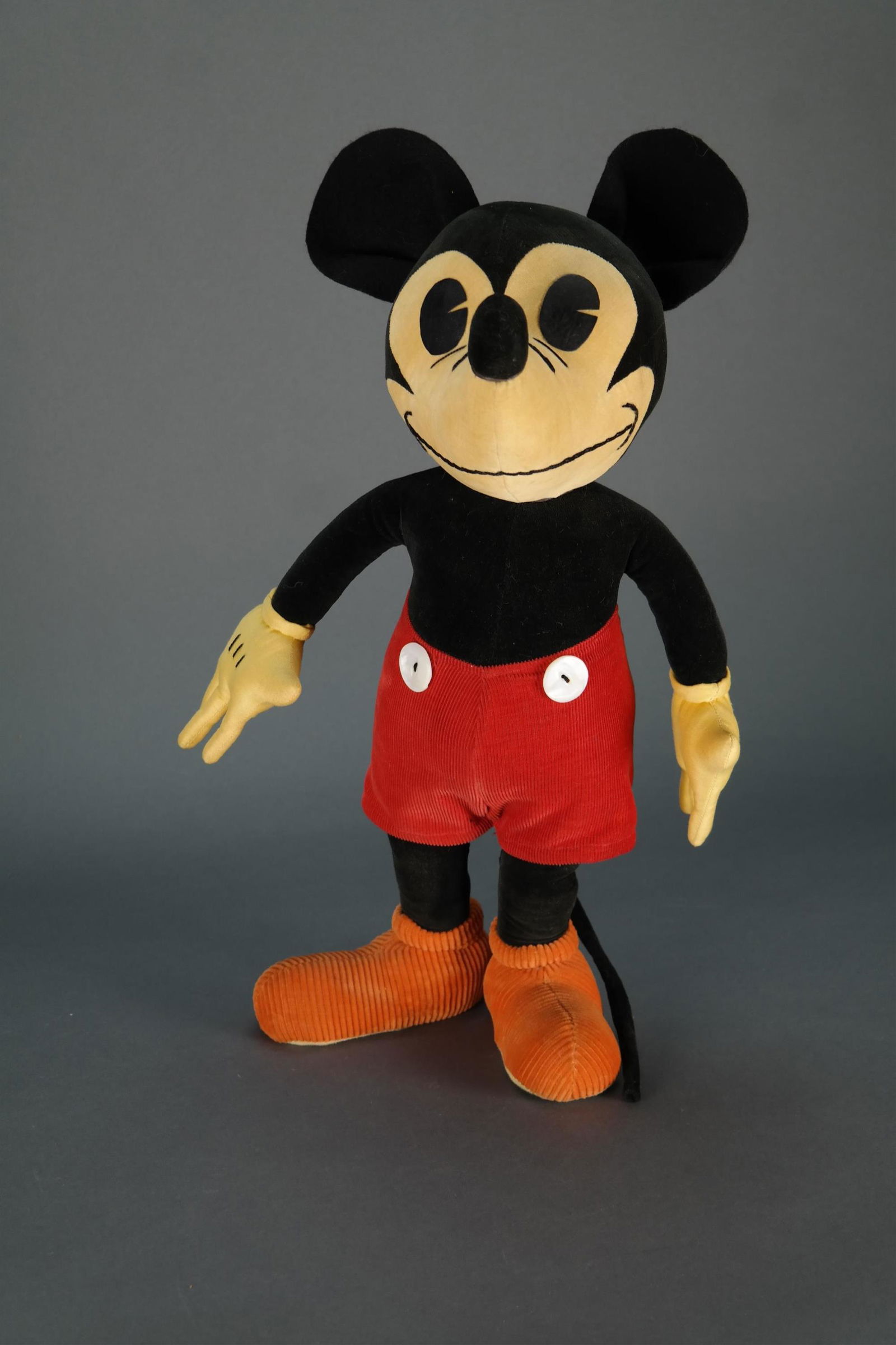 Mickey Mouse Doll. c. 1930s: [Disney] c. 1930s officially licensed Mickey Mouse Doll. Based on the design originally created by Charlotte Clark. Featuring shell buttons, corduroy pants and shoes, and felt ears. Approximately 18"