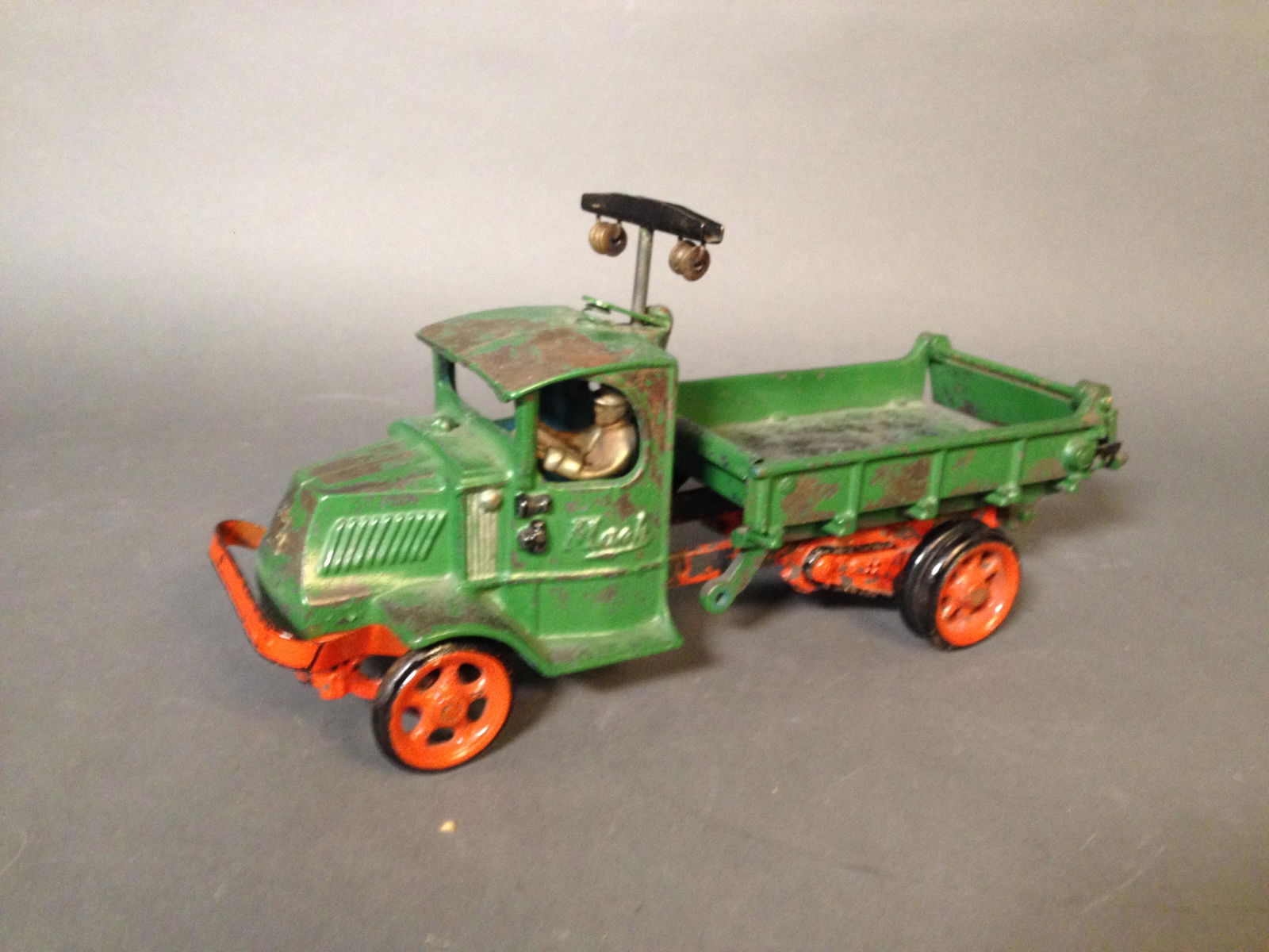 Arcade Cast Iron Mack Spring Operated Dump Truck: Arcade Cast Iron Mack Dump Truck with Spring Loaded Plunger and Integral Figure ++ Marked Arcade inside cab ++ 13" x 5" x 4"_x000D_ Condition: Loss of paint on cab and in truck. Spring mechanism funct
