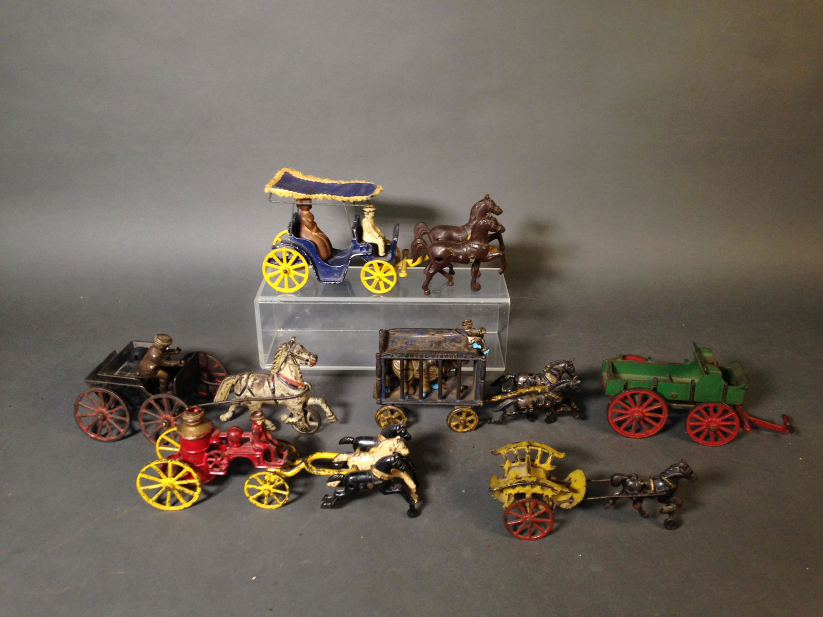 7 Small Cast Iron Horse Drawn Carriages & Carts: 7 Small Cast Iron Horse Drawn Carriages & Carts ++ Royal Circus two horse cart with figure and rhinoceros, 11" long ++ Three horse fire pumper, 11" long_x000D_ Condition: All have wear and paint loss