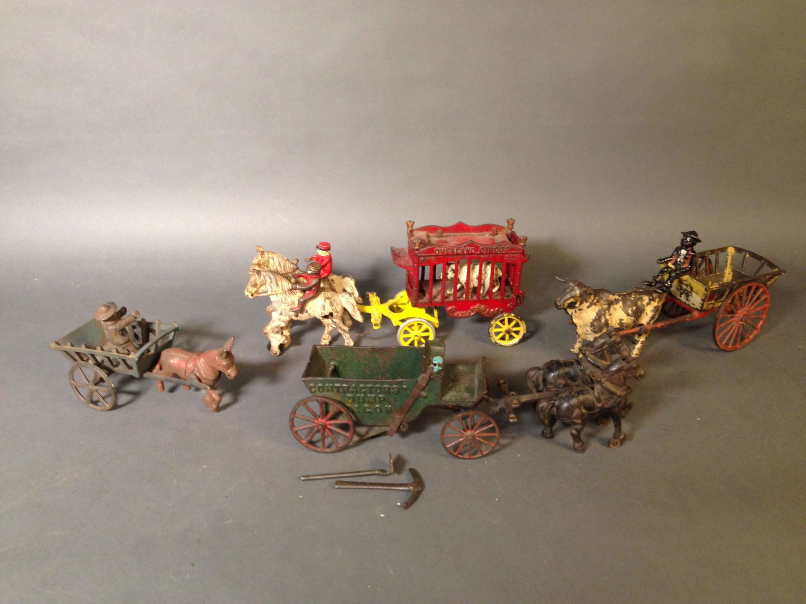 Four Cast Iron Horse Drawn Carts: Four Cast Iron Horse Drawn Carts ++ Kenton Overland Circus cart with two riders and bear figure, 14" long ++ Contractor Dump Wagon with tools, possibly Arcade, 14" long ++ Ox cart with figure, 12 long