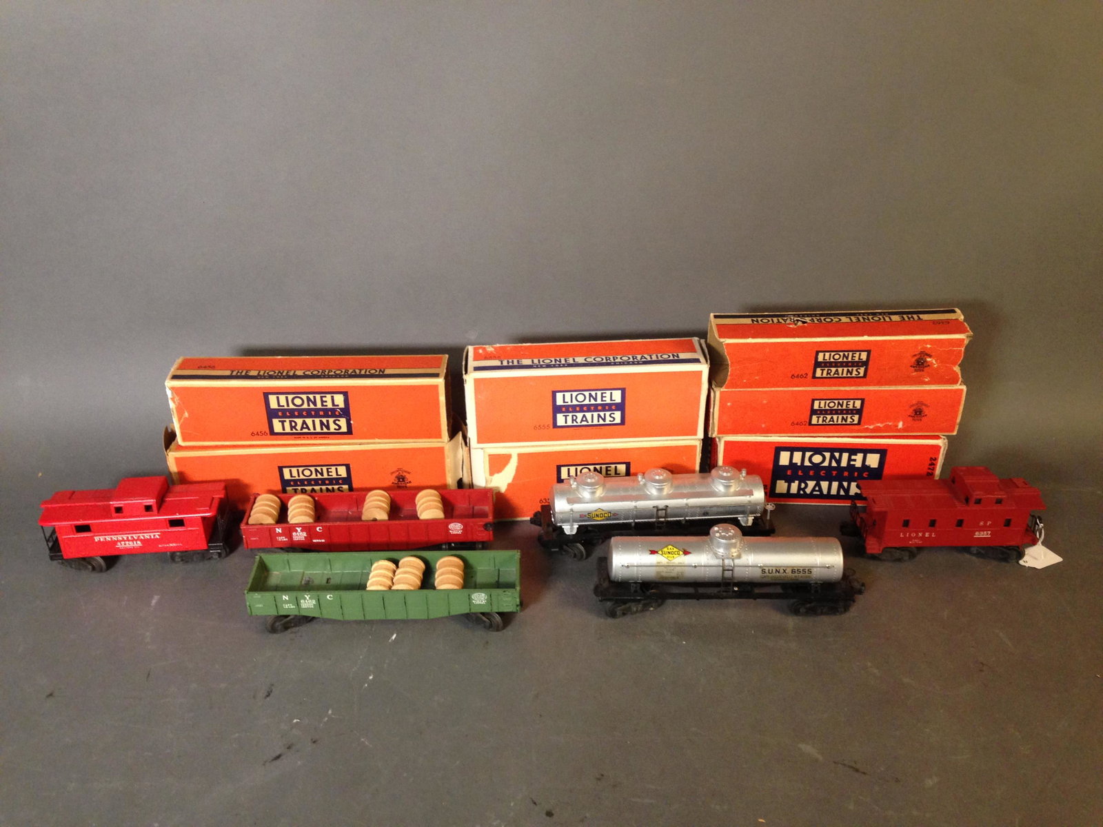 Seven Postwar Lionel Model Train Cars with Box: Seven Postwar Lionel Model Train Cars with Box ++ 6357 caboose, 6555 tank car, sparse 6456 gray hopper car, 6462 black New York Central gondola, 6462 red New York Central gondola, 6415 Sunoco Tank Car