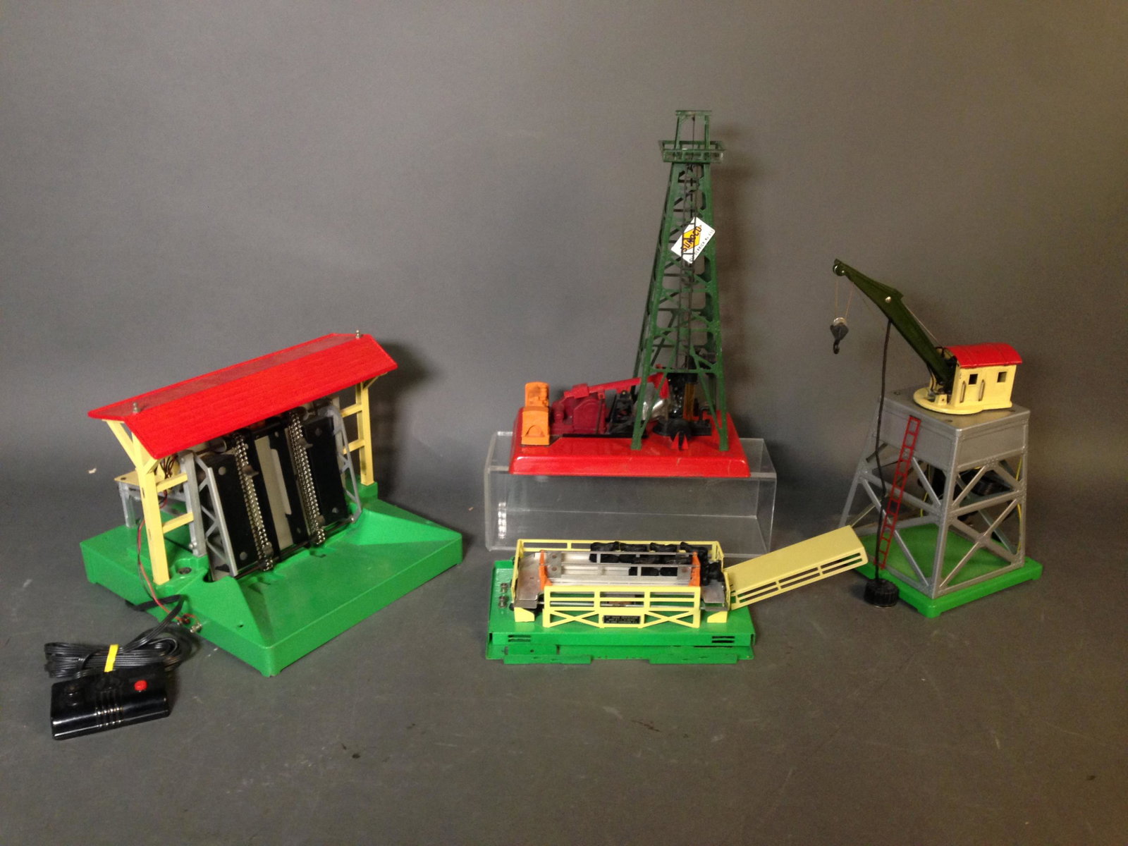 Four Tin Lionel Model Trains Accessories: Four Tin Lionel Model Trains Accessories ++ Postwar 3656 stockyard with 7 rubber cattle figures ++ Postwar 455 Oil Derrick and Pumper with four plastic barrels ++ Postwar 164 Lumber Shed with seven lo