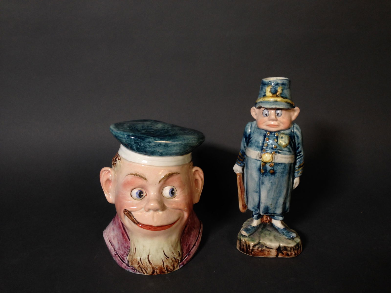 Two Antique Majolica Palmer Cox Brownie Figures: Two Antique Majolica Palmer Cox Brownie Figures ++ Police officer figure with chips to underside of helmet, 8" tall ++ Lidded container in shape of a head, 8" tall
