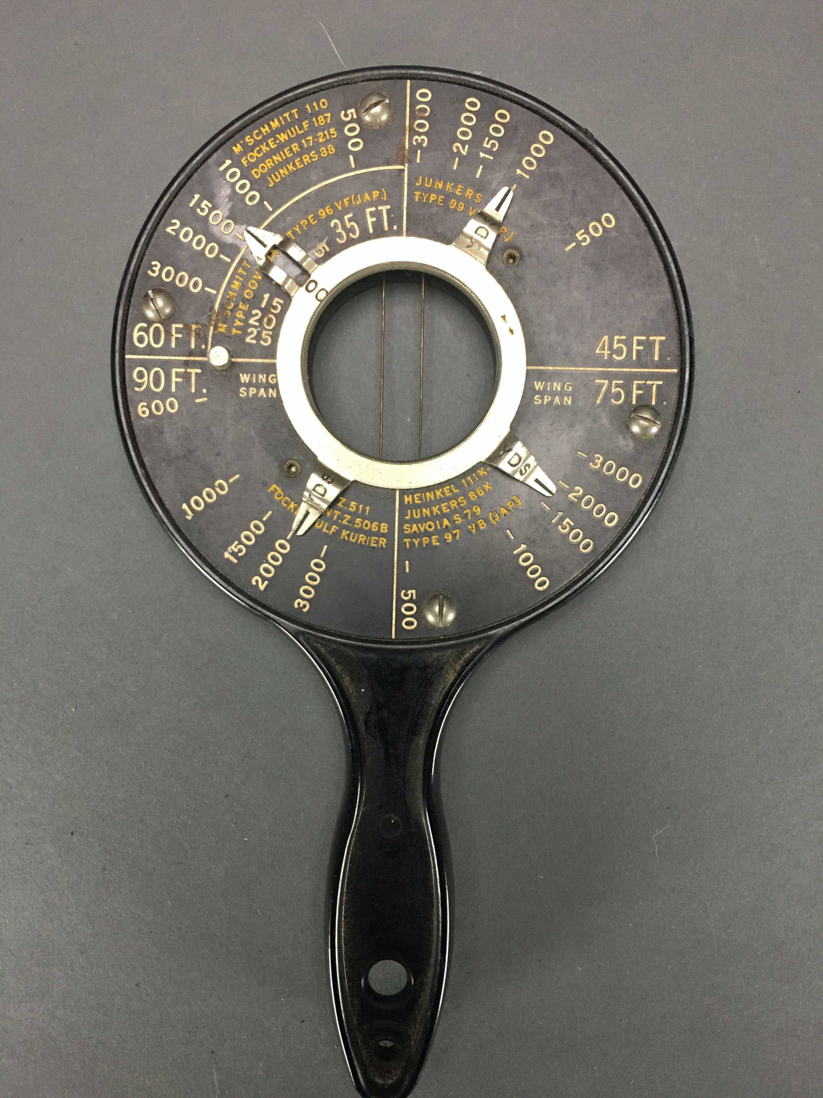 WWII Navy Hand-Held Range Finder.: [Gear/Supplies] WWII U.S. Navy hand-held range finder for anti-aircraft gunnery. Fifteen aircraft are listed on the range finder with various distances attributed to various groups and by pre-identify