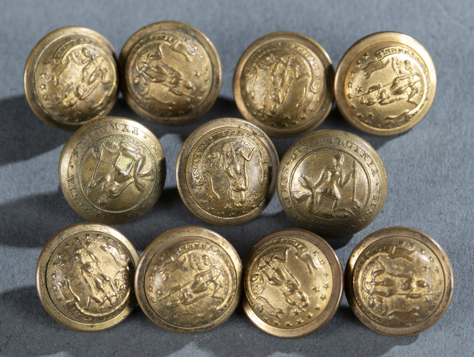 11 Waterbury Co., Virginia Buttons.: [Uniforms] A group of eleven Waterbury Button Co. Virginia state seal buttons. Depicts Virtus slaying tyrant with state motto. Marked on front "Virginia Sic Semper Tyrannis." Marked on back "SCOVILL M