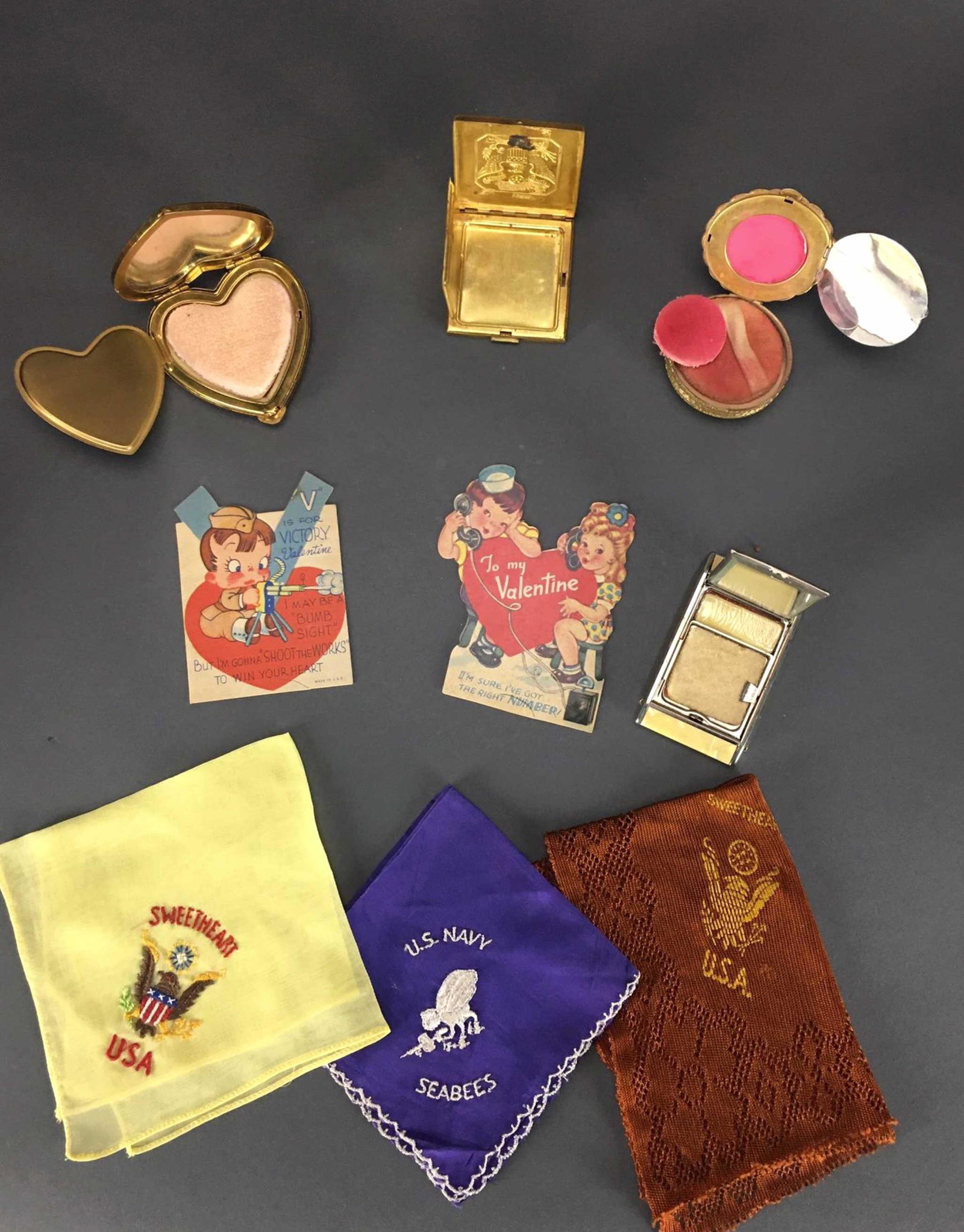 4 WWII Make Up Compacts & 3 Sweetheart Kerchiefs.: [Ephemera] 4 WWII Ladies items. 4 makeup compacts. 3 Army, 1 Navy. 2 with makeup still inside, 1 with blush unopened. ++ 3 Sweetheart kerchiefs. ++ 2 WWII Valentines._x000D_ Condition Very good. Wear 