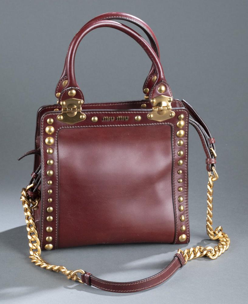 Miu Miu, leather satchel handbag.: A Miu Miu leather studded satchel handbag. Burgundy leather with brass tone hardware/fittings and zipper closure. Detachable leather and chain shoulder strap. 8 1/4" x 8 1/4". Condition: Wear consiste