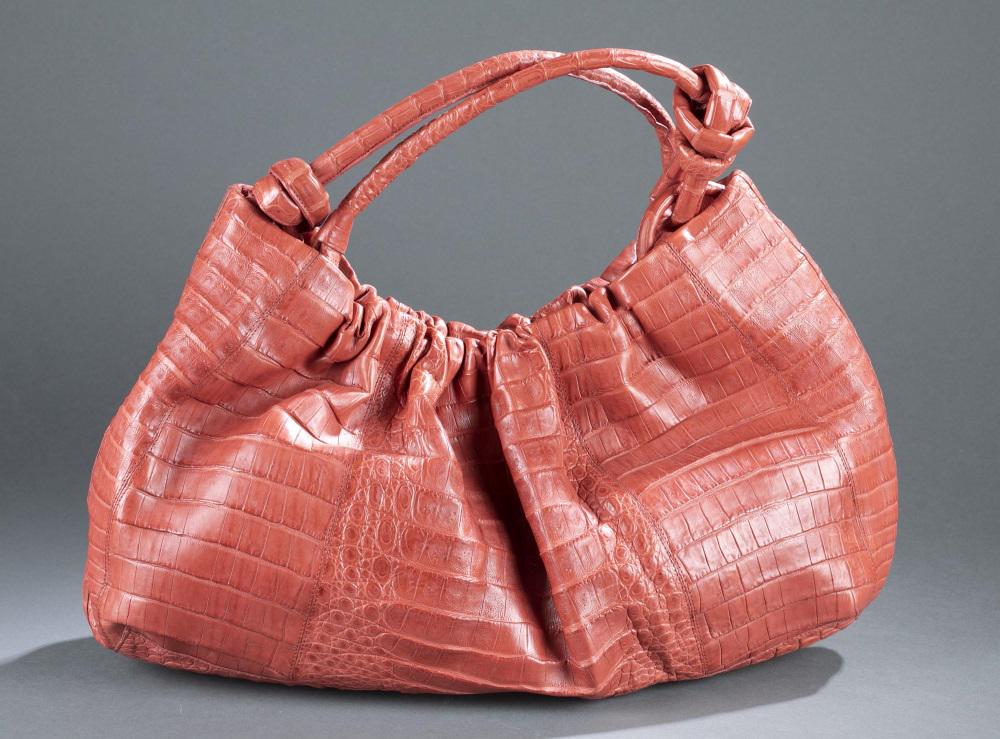 Nancy Gonzalez, Crocodile handbag.: A Nancy Gonzalez crocodile handbag. Red leather and magnetic closure. Knotted end should straps. 11" x 18". Condition: Includes dust bag.