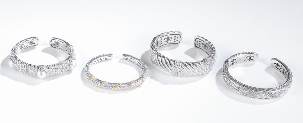 4 Judith Ripka, sterling silver cuff bracelets.: A group of four Judith Ripka sterling silver hinged cuff bracelets. Stamped inside cuff. ++ Bracelet with cord motif and cubic zirconia. 2 1/2". Approx, 68g. ++ Bracelet with diagonal rows of cubic zi