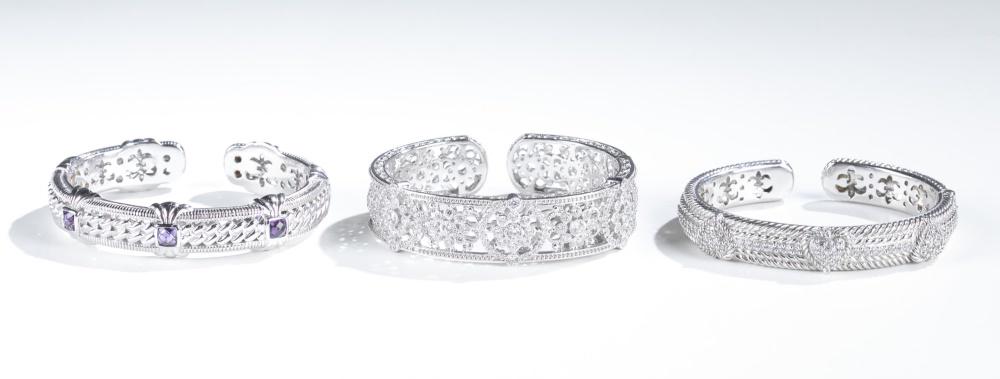 3 Judith Ripka, sterling silver cuff bracelets.: A group of three Judith Ripka sterling silver hinged cuff bracelets. Stamped inside cuff. ++Bracelet with pave hearts of cubic zirconia. 2 3/4". Approx, 46g. ++ Bracelet with amethyst stones. 2 3/4".