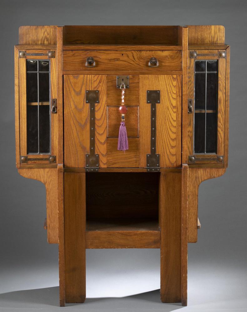 Arts & Crafts, oak desk.: An Arts and Crafts oak desk. 19th/20th century. Strap-hinge drop front desk flanked with glazed door cases. Desk interior has series of pigeon holes, and drawers. 57" x 43" x 17". Shipping: This lot d