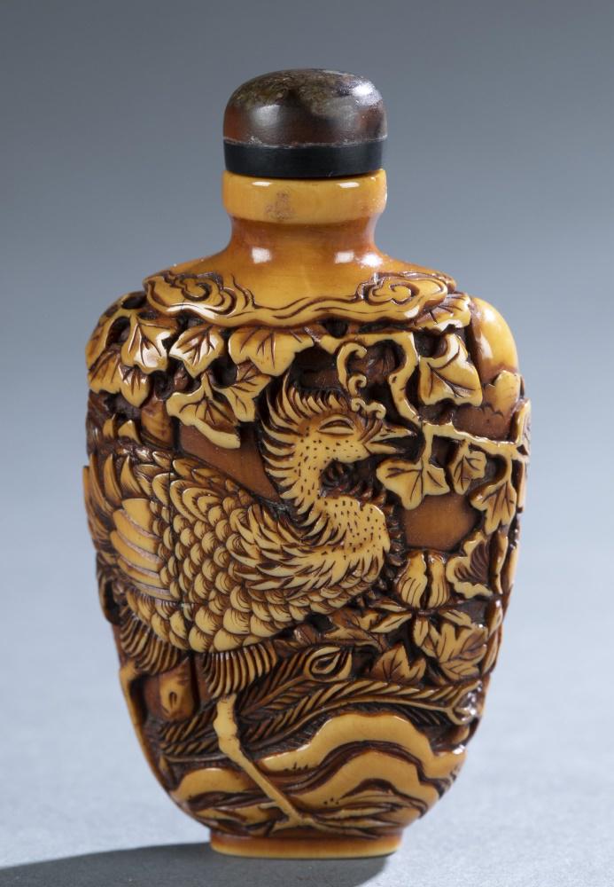 Carved snuff bottle, 19th c.: A carved snuff bottle. 19th century. Intricately carved in high and low relief depicting a phoenix on both sides. Flattened tapering rectangular form with raised oval foot and brown stopper. 2 7/8". 4