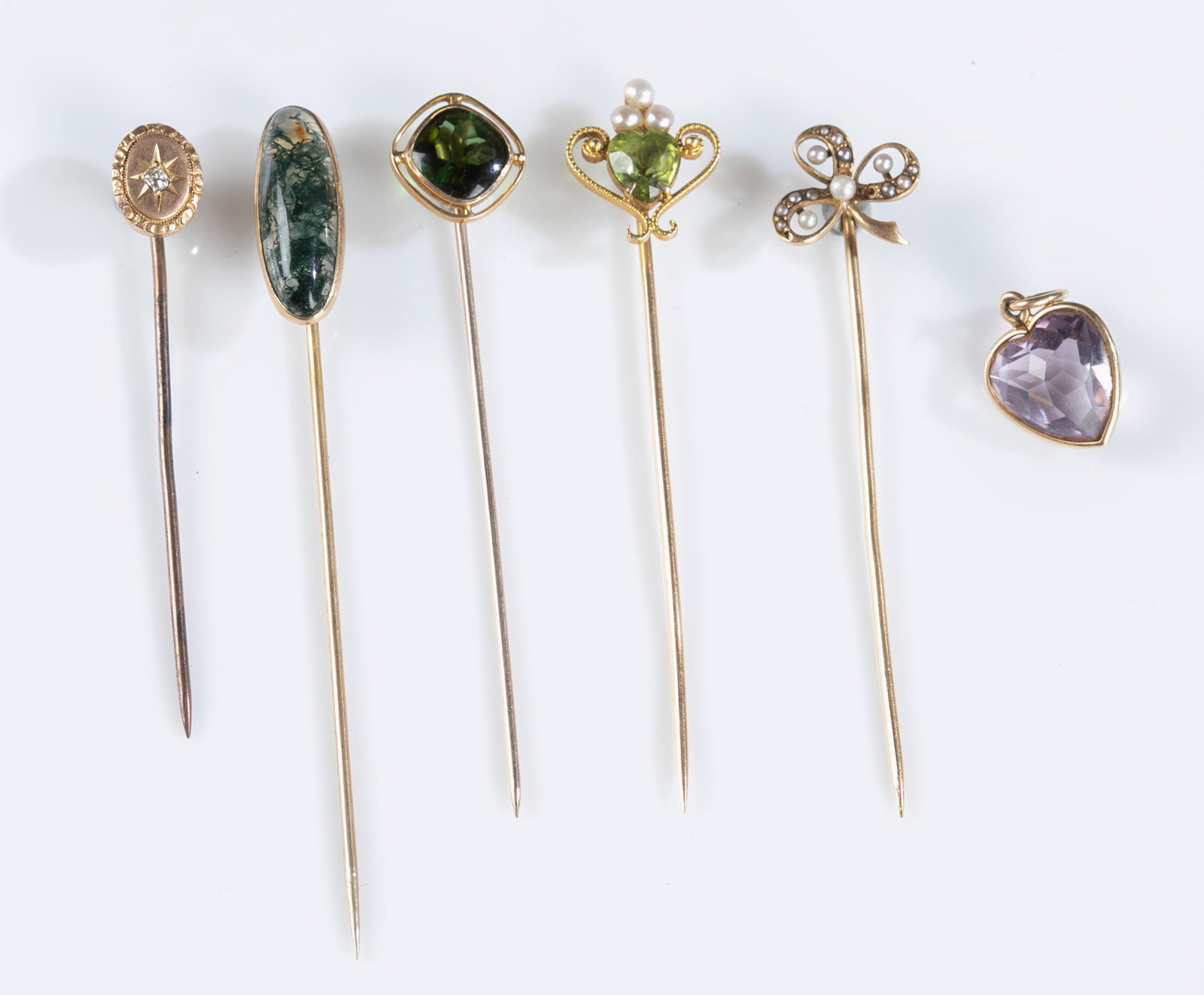 5 Gold stickpins and one pendant.: A group of five yellow gold stickpins and one pendant. ++14k stickpin with a heart shape Peridot in a heart shaped setting. Unmarked, tested 14k. Approximately 2 5/8" and 2.0g. ++14k stickpin with pea