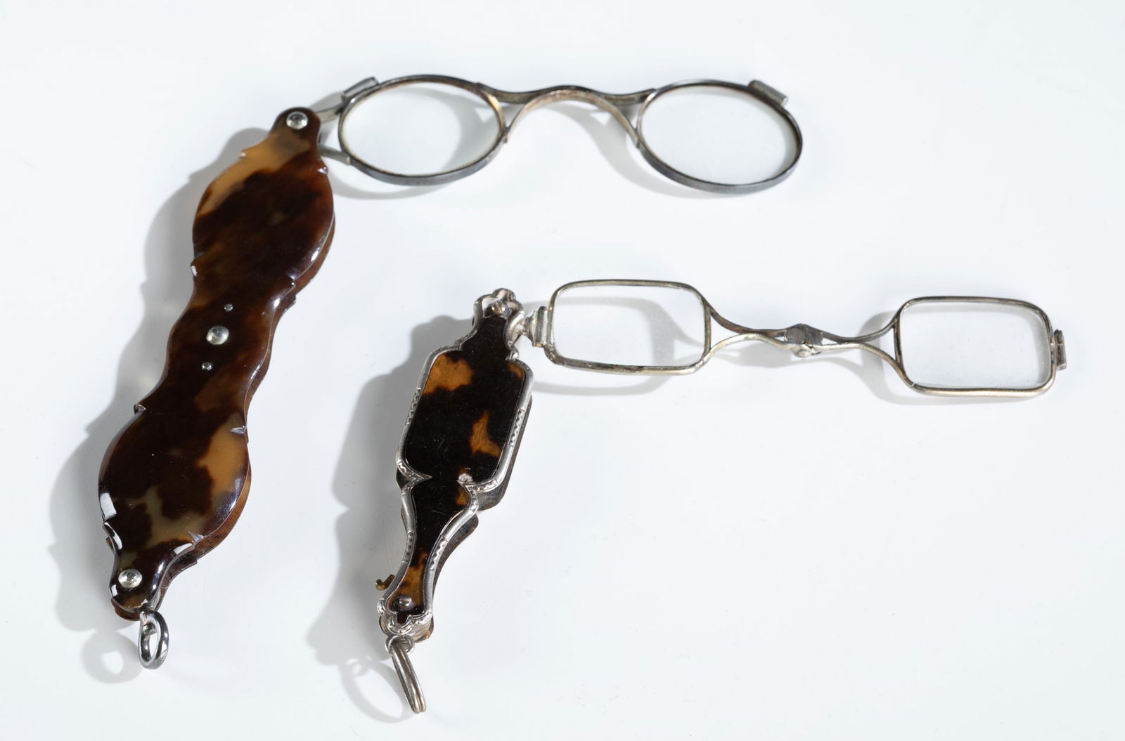 2 Victorian tortoise shell opera glasses, 19th c.: A group of two pairs of Victorian tortoise shell and sterling opera glasses. 19th century. Both with tortoise shell and silver cases. Glasses fold out. Larger pair: 4 1/4" x 1" x 1/4". Smaller pair: 3