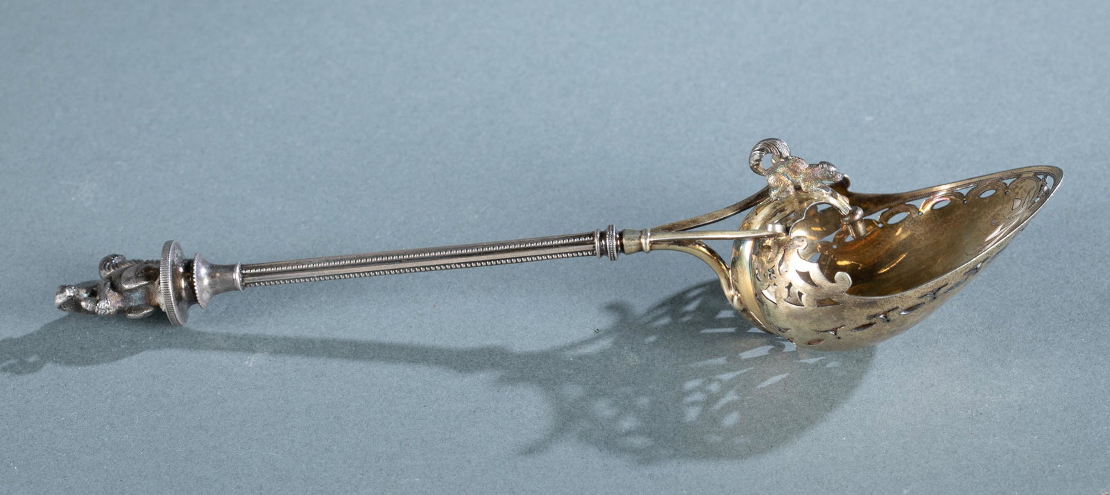 George B. Sharp gilt silver hooded nut scoop.: A George B. Sharp, Philadelphia gilt silver hooded pierced nut scoop, circa 1862-1874. Scoop has applied squirrel on finial and also on hood of spoon which ends in an acorn. Marked on underside of bow