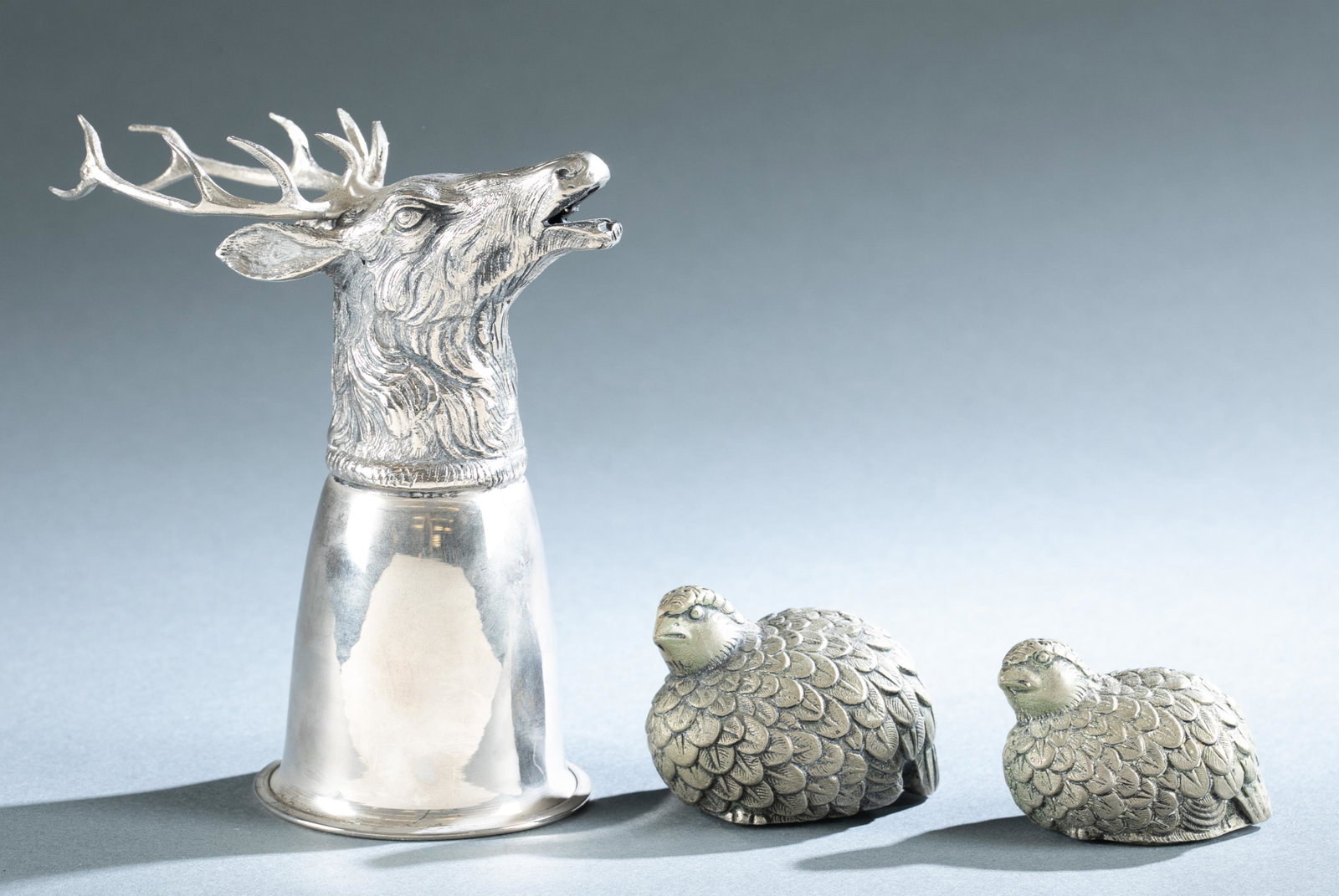 3 Gucci metal pieces.: A group of three Gucci metal pieces. ++ Stag's head silverplate stirrup cup. Stamped Gucci and Italy on edge of stag's head. 6 1/8" x 5 1/2" x 3 1/8" ++ Pair of seated quail salt and pepper shakers. M