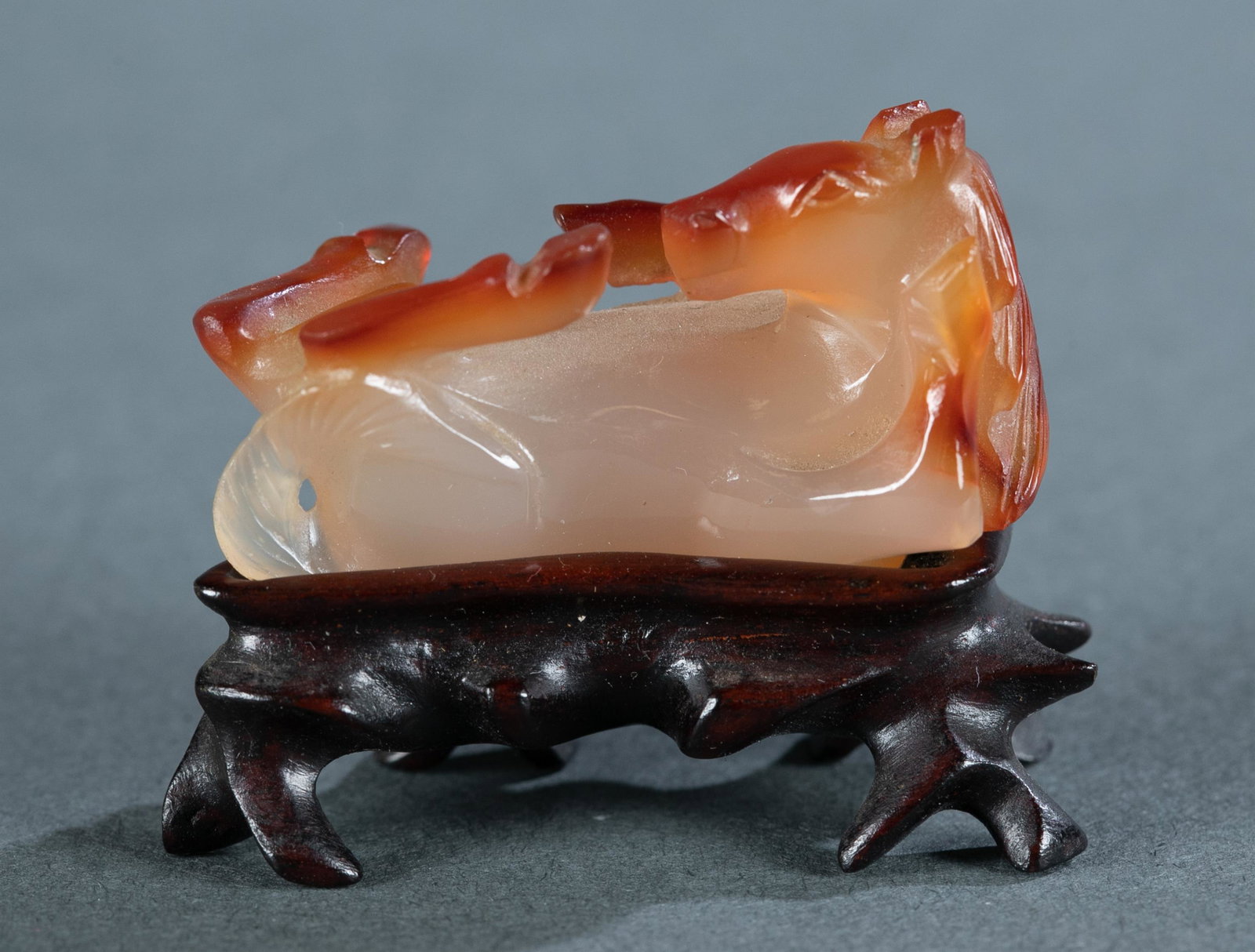Small agate figure of a reclining horse, 20th c.: A small agate sculpture of a reclining horse. 20th century. A horse laying on his back with feet in the air. Comes with wooden base. 1 1/8" x 1 1/4" x 1". With base: 1 5/8" x 2" x 1".