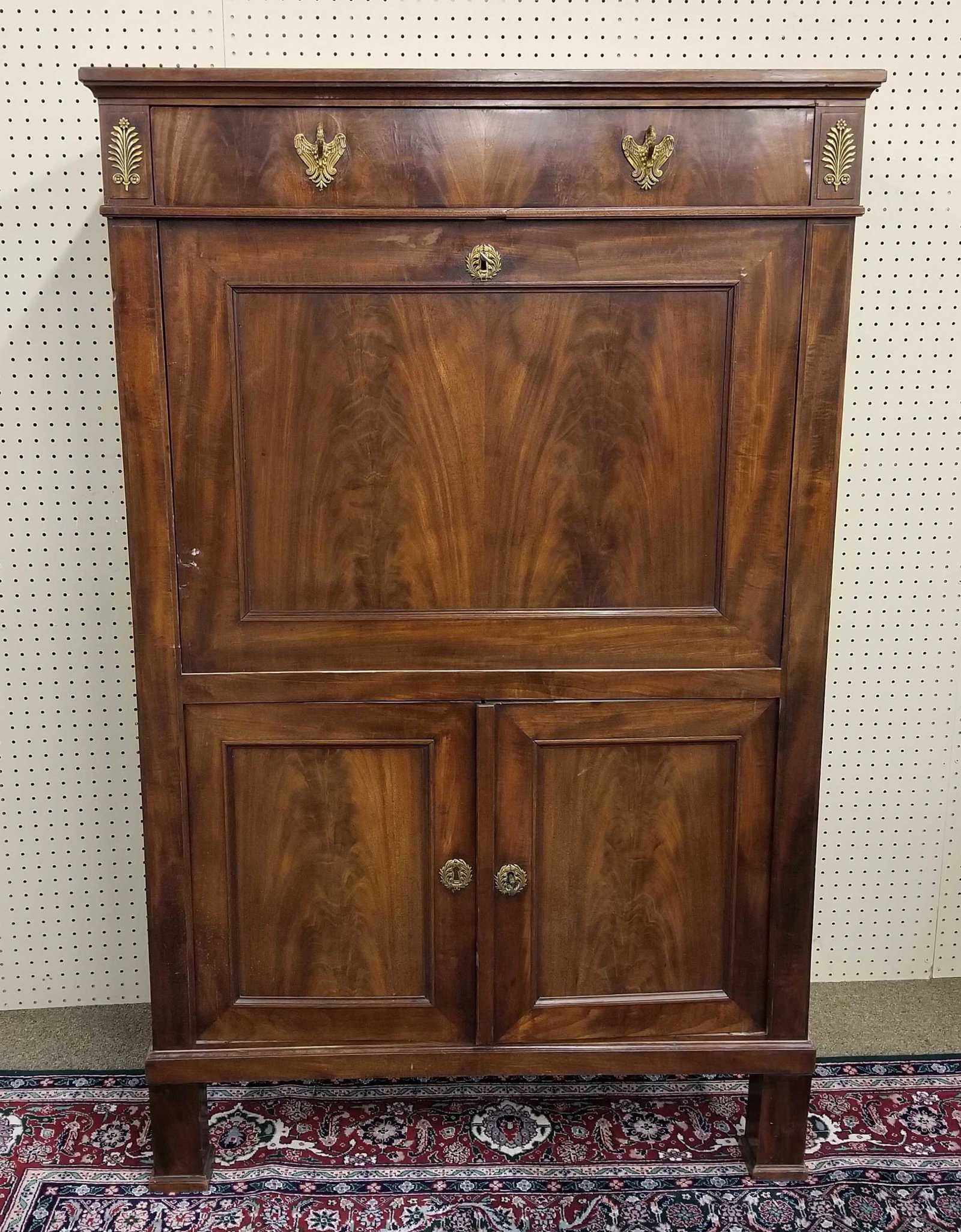 French Empire secretaire a abattant, 19th c.: French Empire flame mahogany veneer secretaire a abattant, 19th c. Top drawer has brass eagle form pulls between floral brass mounts, drop down leather desk with brass escutcheon with four drawers, ov