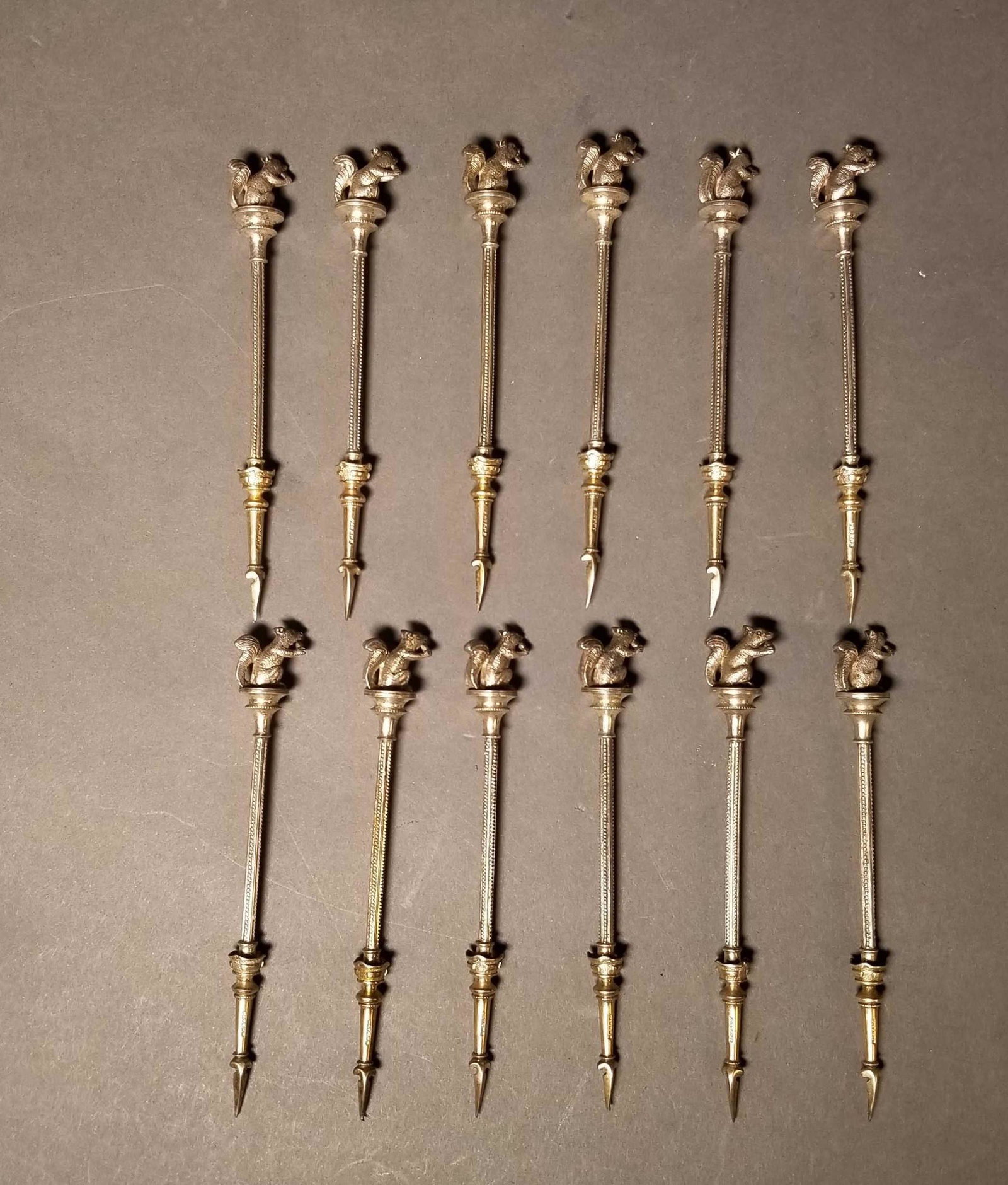 12 American silver nut picks, 19th c.: A group of twelve American silver squirrel finial nut picks, circa 1844-1874.. Attributed to George B. Sharp, Philadelphia. Each have a applied squirrel finial with a gold wash pick. Marked "Patent" o
