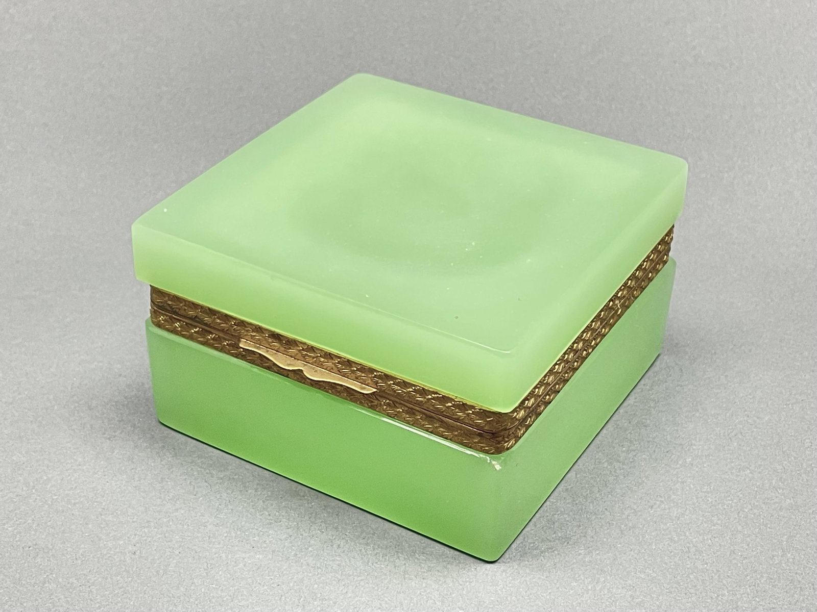 Green Opaline glass casket box.: Opaline blown-glass casket box with gilt hardware. Light green color. 4 1/4" x 4 1/4" x 2 1/2". Condition: Very good. One corner of base chipped