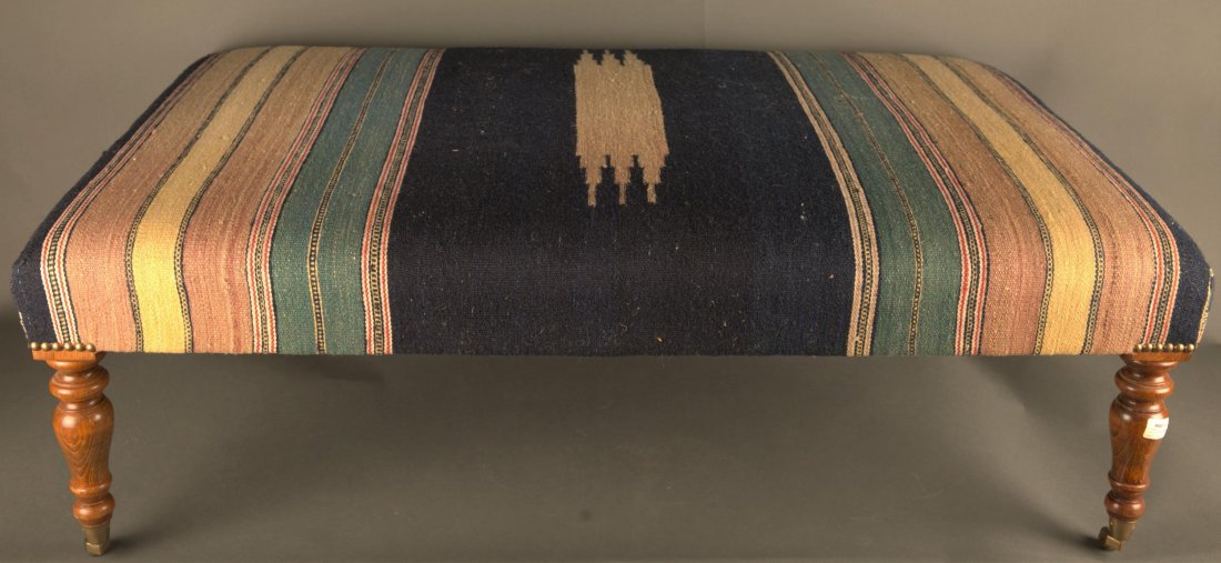 Upholstered ottoman.: A large rectangular rug upholstered ottoman. English mahogany frame with turned legs on casters. 45 1/2" x 14" x 28". Provenance: The Estate of Giraud V. Foster.