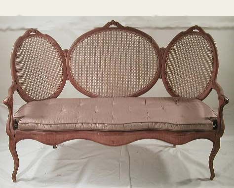 Two American oak framed triple oval back: Two American oak framed triple oval back settees with carved design at top of ovals, arms ending in cabriole front legs, major repair done to both, caneing bad on 1 seat and on other set of backs, mid