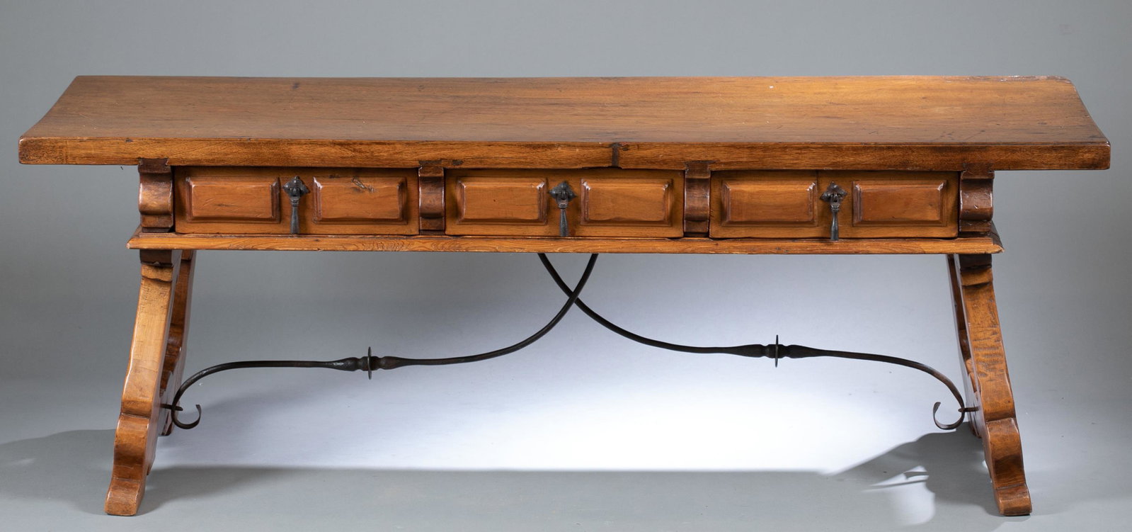 Spanish Colonial style bench.: A Spanish Colonial style bench. Three drawers raised on two harp legs with wrought iron stretcher. 22" x 61" x 19 3/4".