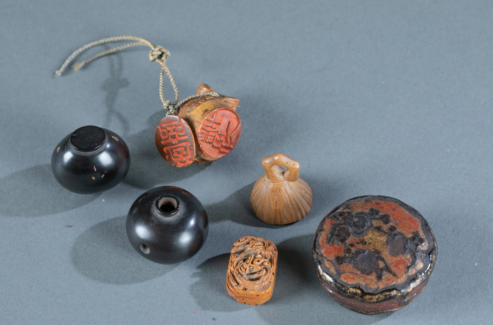 Group of 6 small misc netsuke items.: Group of 6 misc netsuke items. Including one natural bamboo seal netsuke. 1 3/8". 2 black wood mini containers. Taller one: 1". One wood lotus fruit. 1". One wood seal carving a twisted dragon on the 