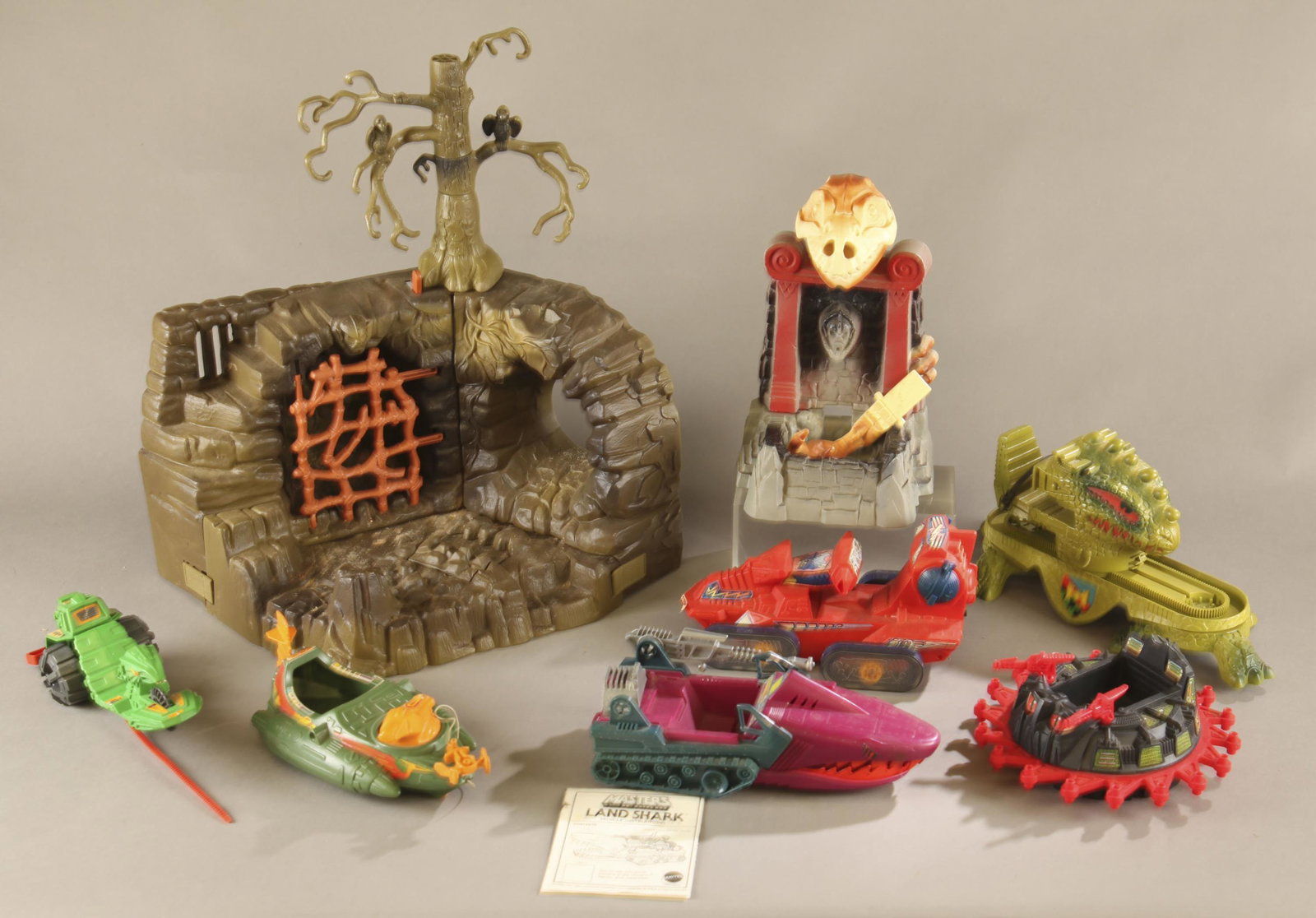 2 Original MOTU playsets and 5 vehicles.: A group of two original Mattel Masters of the Universe playsets and seven vehicles. ++ 1984 Fright Zone playset. Includes tree with one broken crow and prison door. Missing dragon glove. 19" x 18" x 1
