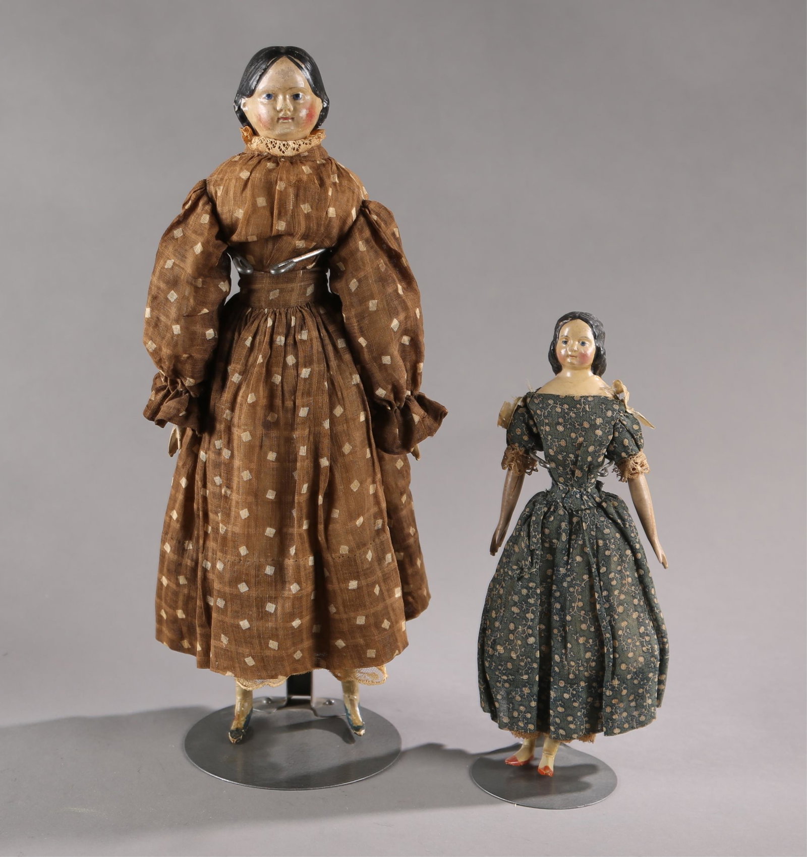 2 German milliners model paper mache dolls.: A group of two German milliners model paper mache doll, Early 19th Century. ++ Paper mache headed doll. Molded side part carved black hair. Leather body with wood limbs. Includes petticoat and dress. 