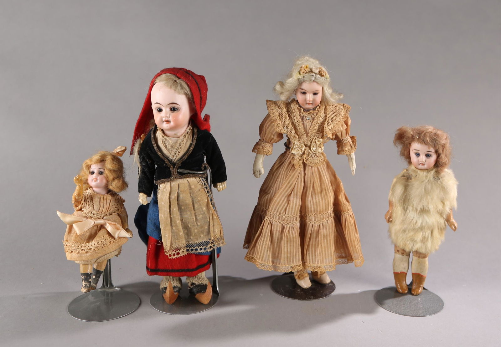 4 Bisque headed small dolls.: A group of four bisque headed small dolls. ++ Armand Marseilles doll. Bisque head with glass eyes and wig. Marked on neck "AM 15/0". Cloth body with leather arms. Leather shoes, bloomers, petticoat, a