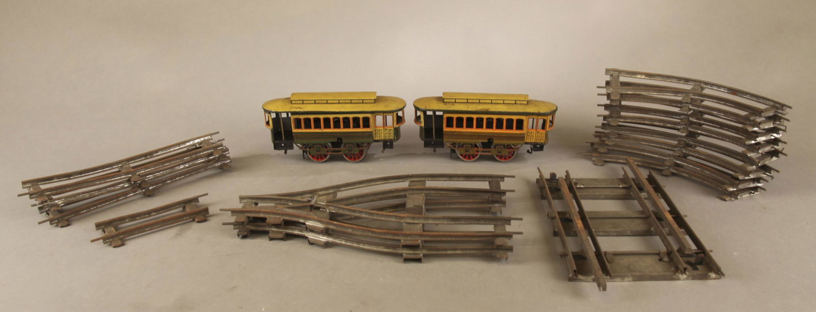 2 Bing clockwork trolley cars with track.: A group of two O Gauge Bing clockwork tin lithograph trolley cars with track. 4" x 8" x 2". Bing marked tracks. Four 10" straight tracks, ten 10" curved track, one 5" straight track, two 13" x 6 3/4"