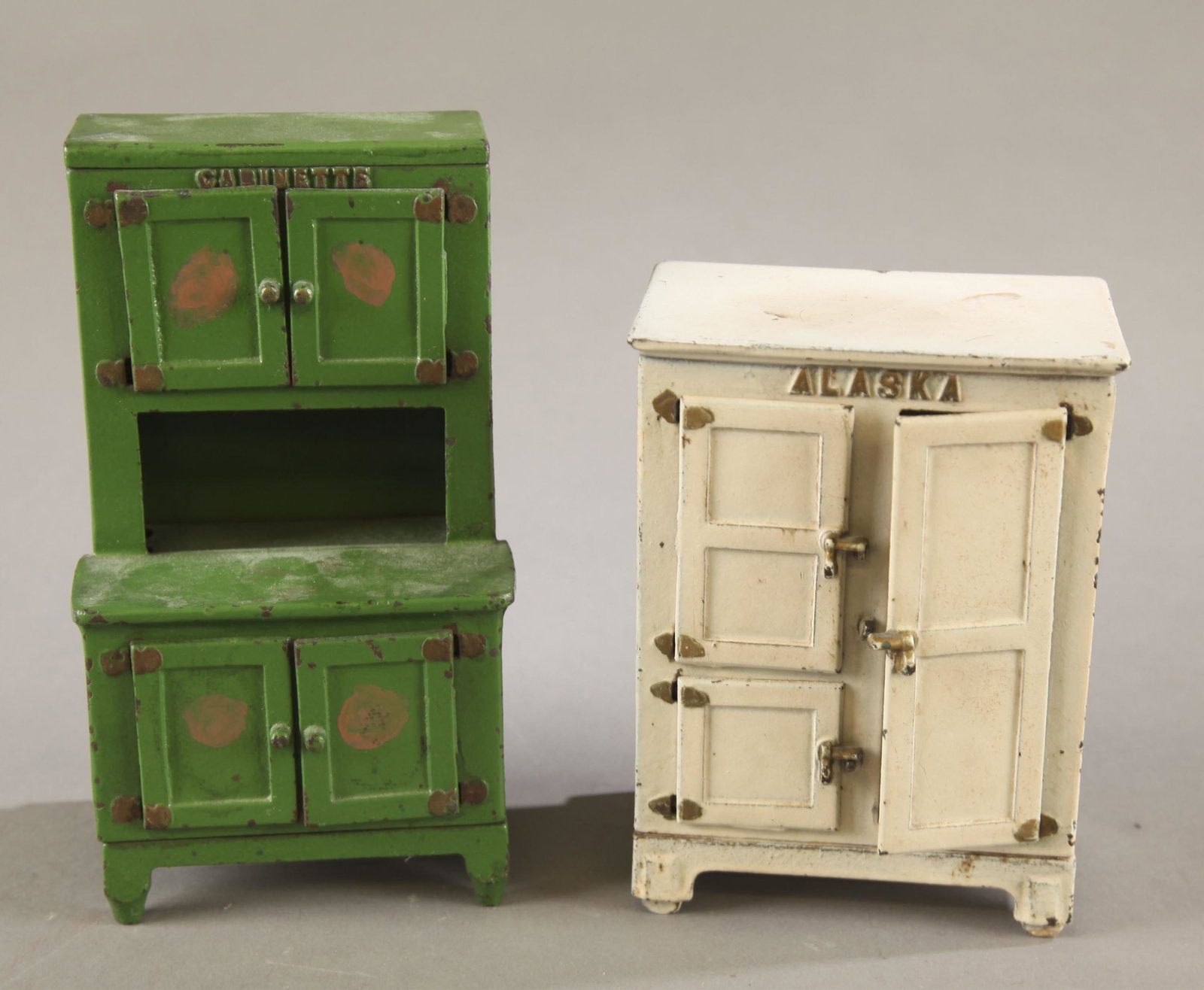 2 Cast iron furniture pieces.: A group of two cast iron furniture pieces. ++ Hubley Cabinette toy. Four doors with two interior shelves. Stamped on bottom 1250. 7 1/2" x 4 1/4" x 3" ++ Arcade Alaska three door ice chest. Marked on 