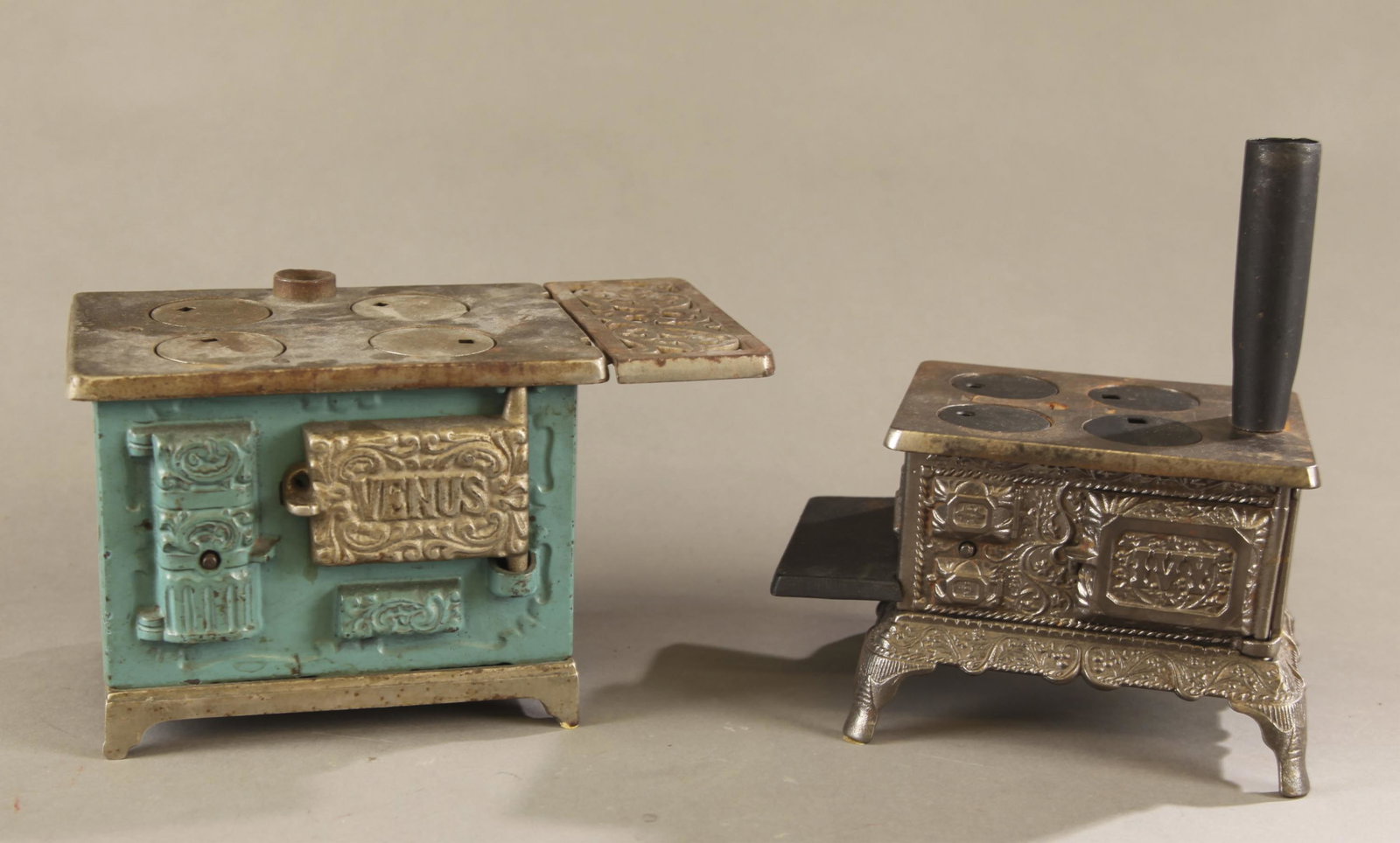2 Cast iron toy coal stoves.: A group of two cast iron toy coal stoves, Circa 1920. ++ Kenton "Venus" cast iron partial nickel plated four burner stove. Includes grate. 5 1/4" x 8 1/2" or 6 1/2" x 4 1/2" ++ J and E. Steven "Ivy" c