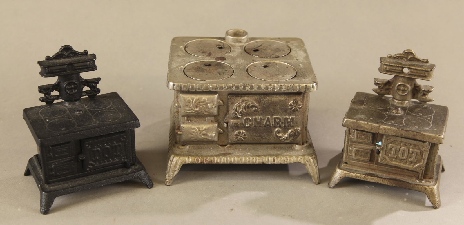 3 Cast iron coal toy stoves.: A group of three cast iron coal toy stoves. ++ "Charm" four burner nickel plated cast iron stove. Includes four burner plates. 3 3/4" x 5" x 5". ++ "Dot" black four burner cast iron stove. Includes ba