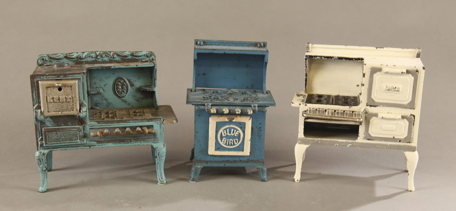 3 Cast iron toy gas stoves.: A group of three cast iron toy gas stoves, Early 20th Century. ++ Kenton "Kent" cast iron gas stove. 5 1/2" x 6 1/4" x 3". ++Grey Iron "Blue Bird" cast iron gas stove. 6 1/4" x 4" x 3 1/4". ++ Arcade 