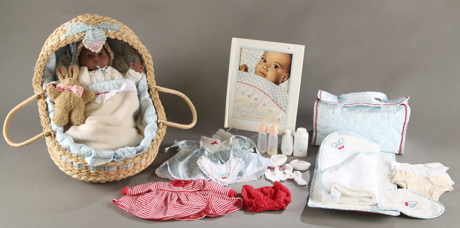 African-American Our New Baby doll and accessories: Pleasant Company African-American Our New Baby doll and accessories, circa 1990-1995. The precursor to Bitty Baby. 15" doll dolls knits including sweater, bonnet, and booties. Lullaby basket, includin