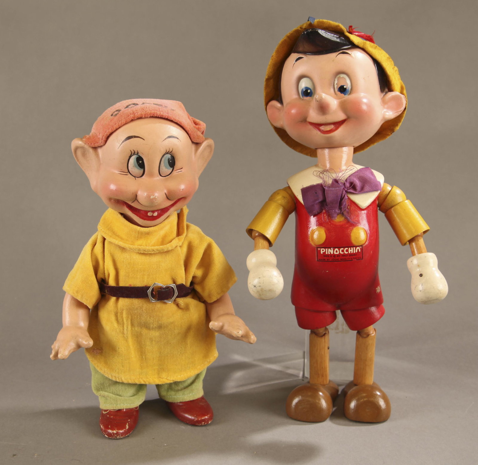 2 Disney composition figures.: A group of two Disney composition figures. ++ Ideal Toy & Novelty Co. Pinocchio composition and wood doll. Composition head with felt hat and composition body and silk bow tie, wood jointed limbs. Mar