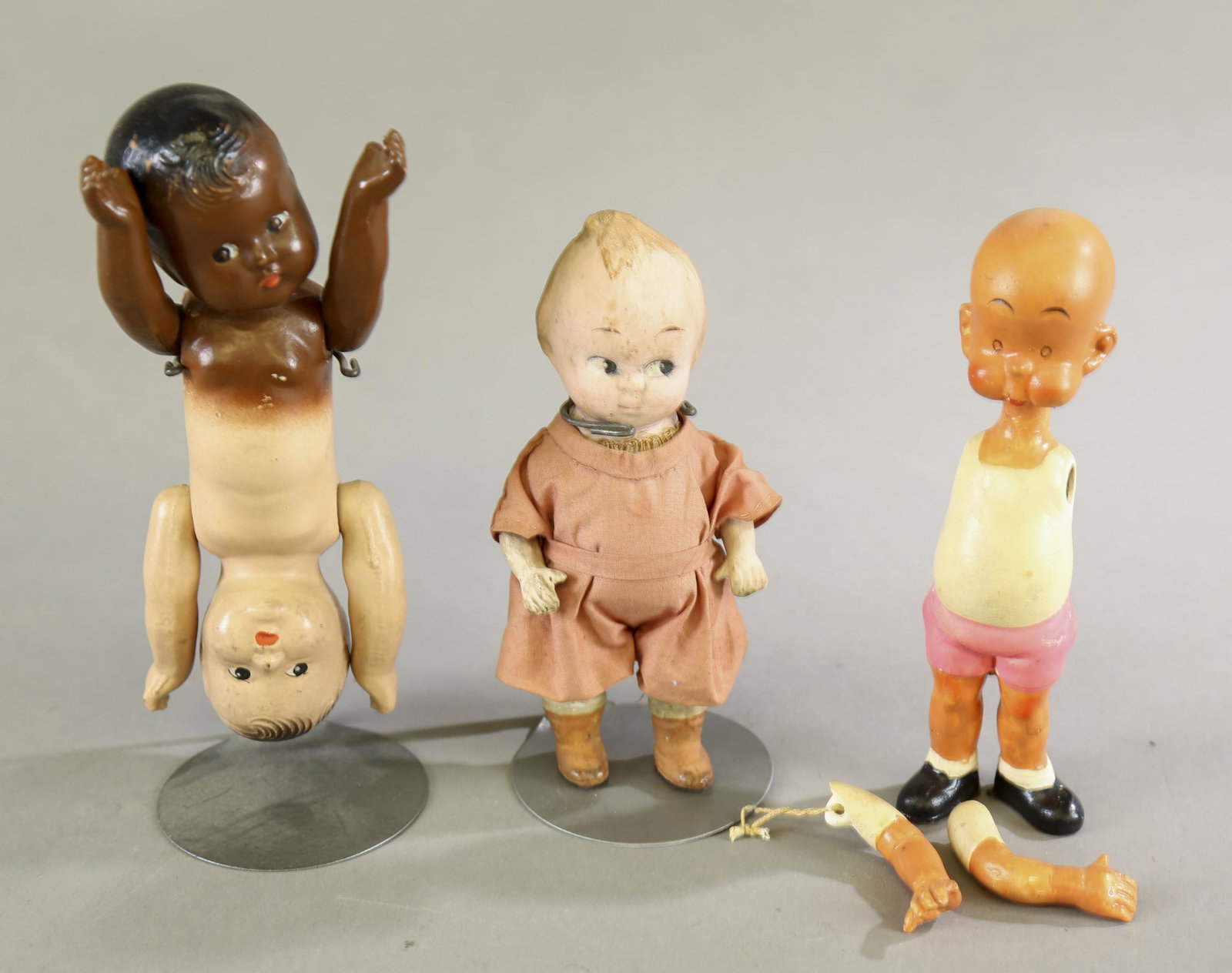 3 dolls.: A group of three dolls. ++ Bisque Carl Thomas Anderson "Henry" doll. Marked "Japan" on feet and on back. 6 3/4" tall. ++ Composition Topsy Turvy dolls. 7" long. ++ Composition Kewpie doll. Fully joint