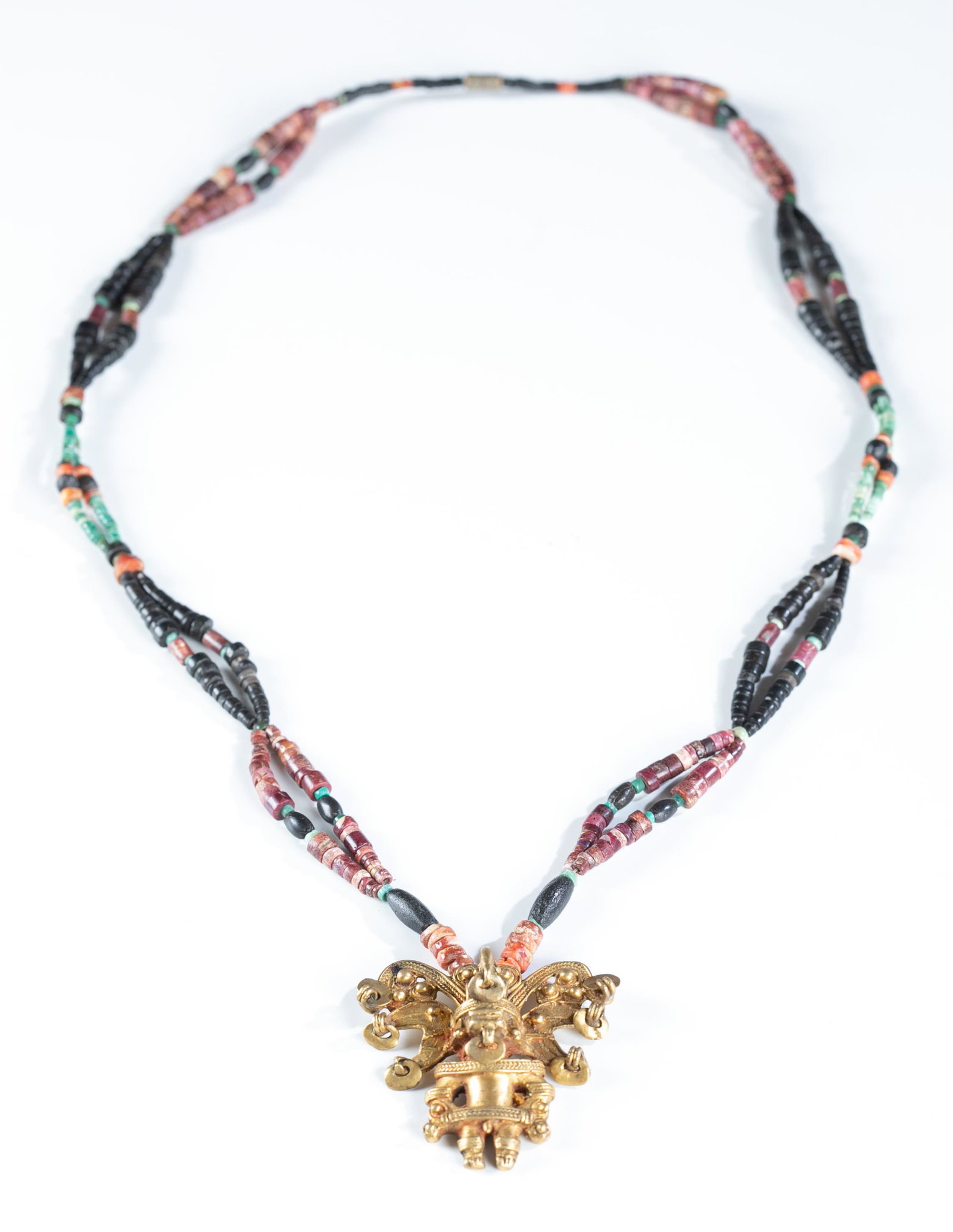 Veraguas style beaded necklace.: A Veraguas (Panama/Costa Rica) style beaded necklace with a gold tone pendant . Barrel clasp. 26 1/4" Pendant: 1 3/4". Provenance: The Estate of Giraud V. Foster.The Estate of Giraud V. Foster.