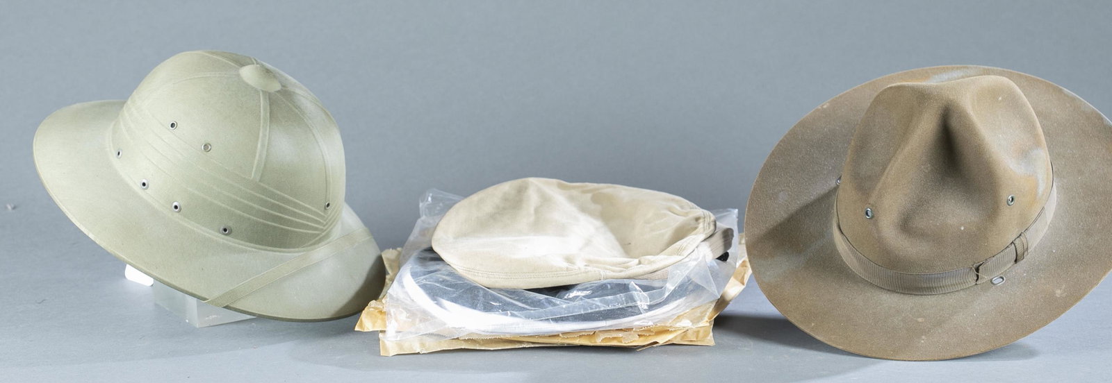 2 WW2 U.S. military hats and nine hat covers.: A group of two WW2 U.S. military hats. ++ U.S. Navy Hawley Products pith helmet, dated 1944. Includes original tag with resizing instructions. 6 1/2" x 24" x 11 1/4". ++ WW2 U.S. Army felt campaign ha