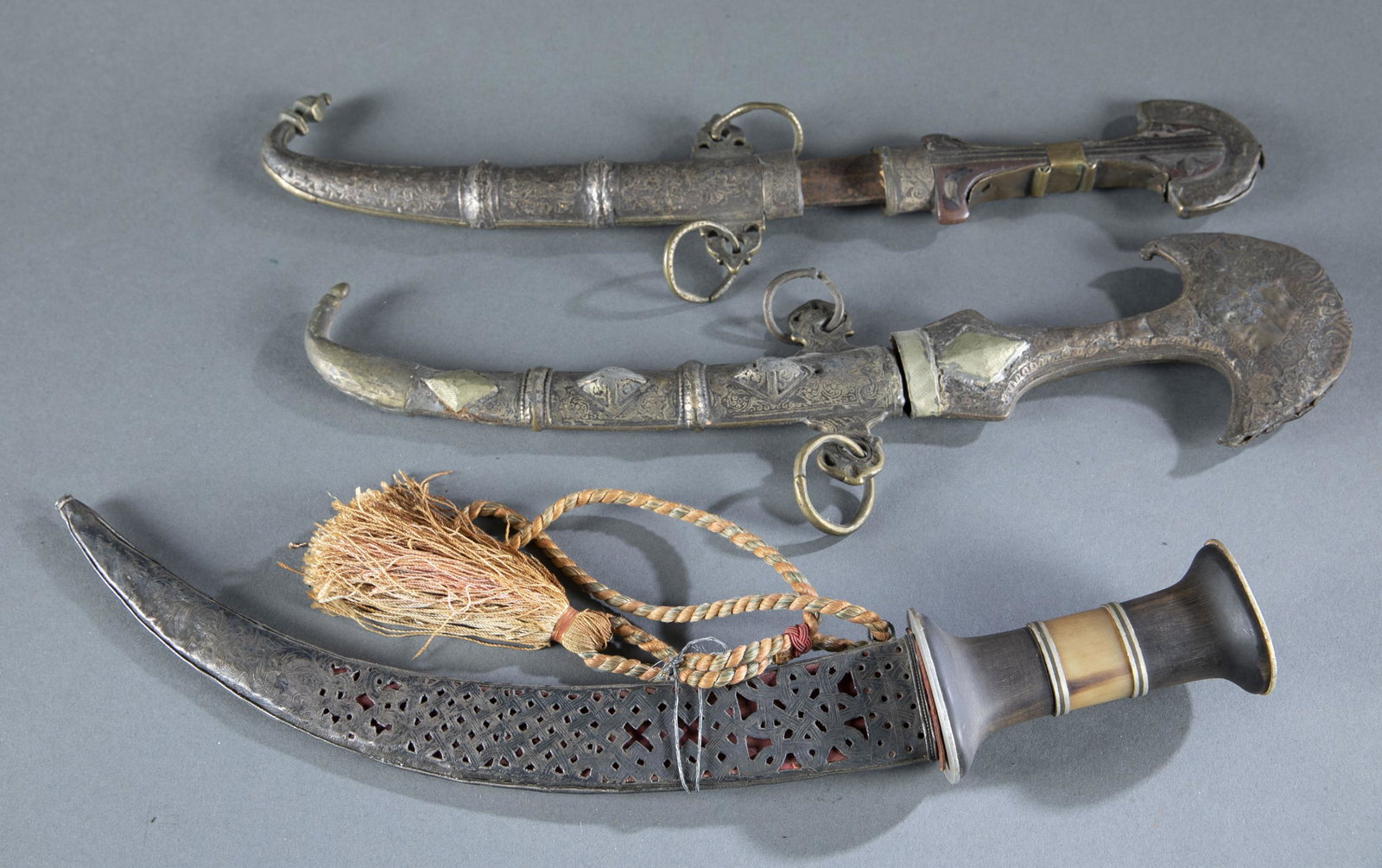 3 North African daggers.: A group of three North African daggers. ++ Moroccan koummiya or koummya dagger. Brass and silver sheath. 8 3/4" blade. Wood handle with silver mounts. 9" sheath and 15 1/4" overall. ++ Unknown dagger.