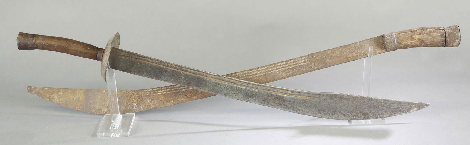 2 Chinese ox-tail dao sword.: A group of two Boxer Rebellion era Chinese ox-tail dao swords, Late 19th Century. Single edged blade, carved wood grip, and metal pommel. One has cupped crossguard and other missing. One has partial e