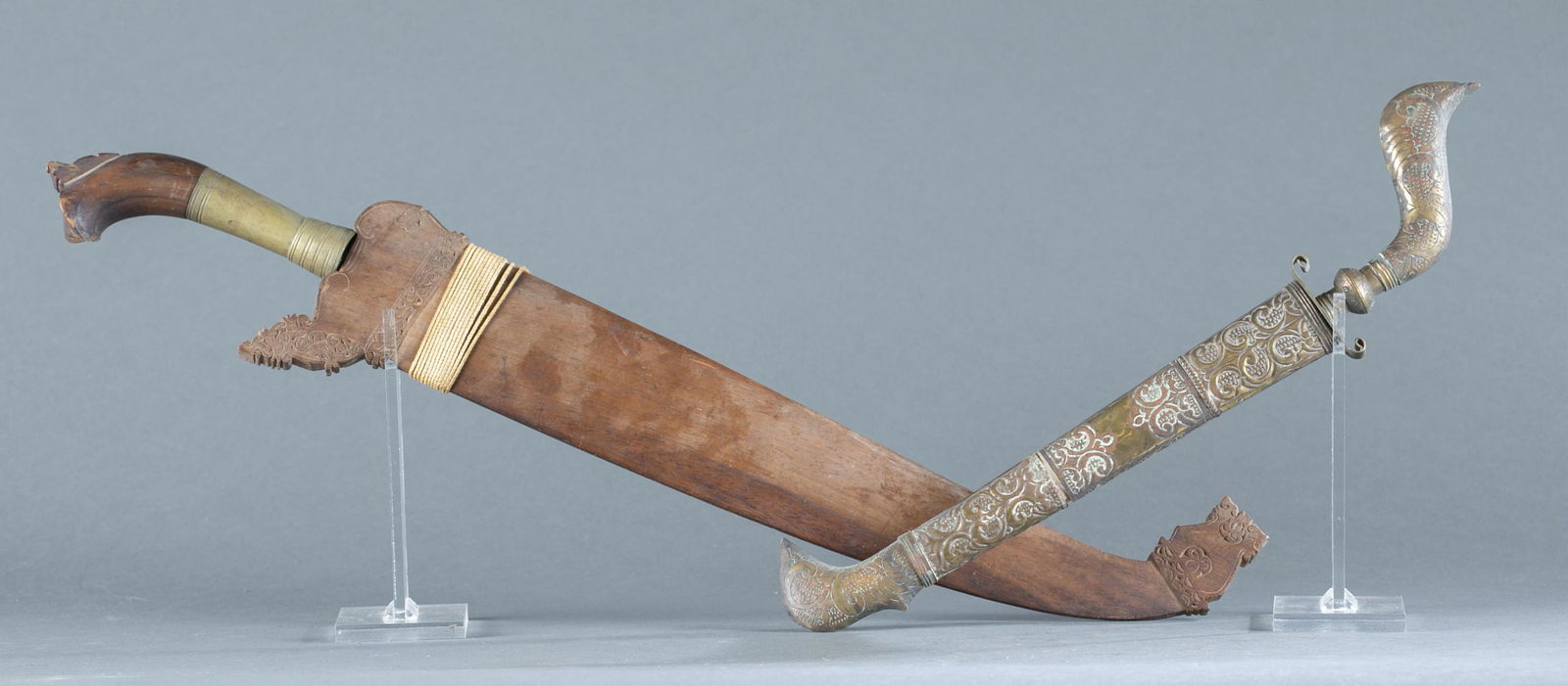 2 Indonesian daggers.: A group of two Indonesian daggers. ++ Philippine Barong knife. 16 1/4" broad leaf blade with wood and brass handle. Wood sheath with decorative carving. 22 1/4" overall and 20" sheath. ++ Bugis badik