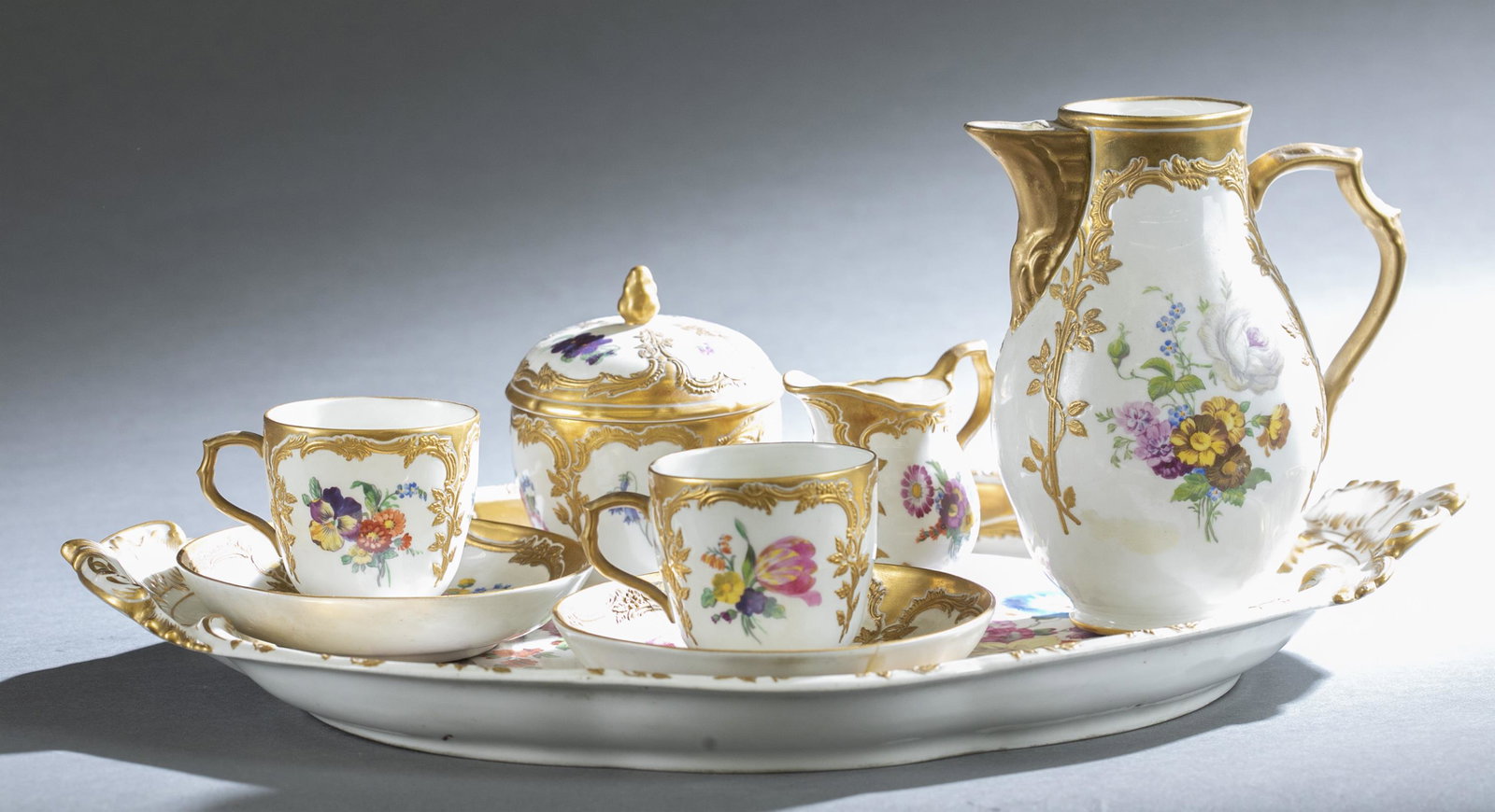 KPM porcelain tea service, 1945-1962.: A KPM porcelain tea service with multi-colored flowers and gold trim. 1945 to 1962. Includes two tea cups 2 1/2" x 3 1/2", two saucers 5" x 5", one creamer 3 1/2" x 3 1/4", one sugar 4" x 3 1/2", one