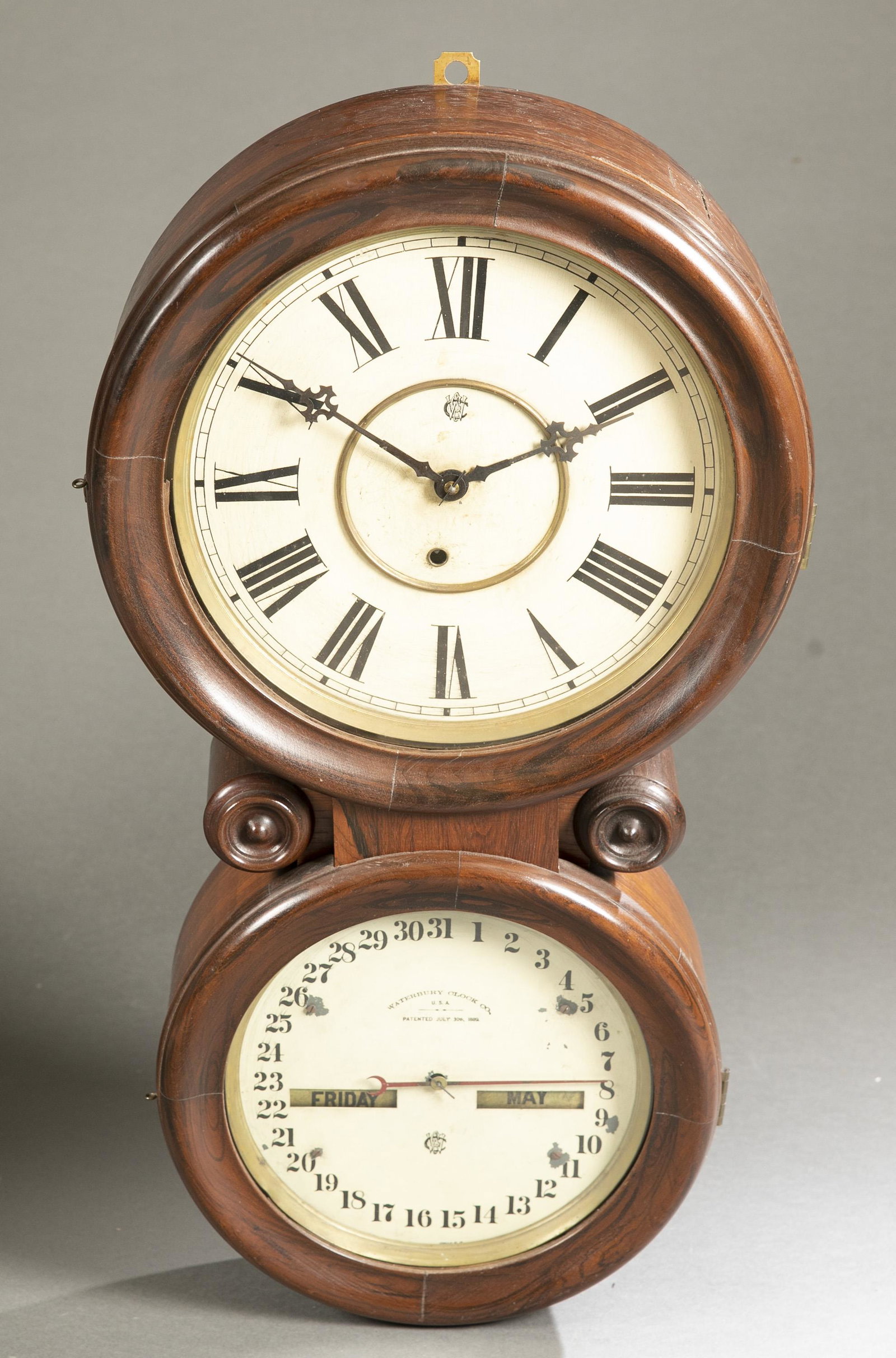 Waterbury No. 34 Calendar wall clock.: A Waterbury No. 34 Calendar wall clock. 8 day time with calendar movement. Painted Roman numerals over Arabic numeral dials. 29 1/2" x 4 3/4" x 15 1/2"Provenance: From the Mike & Jean Clinton Family