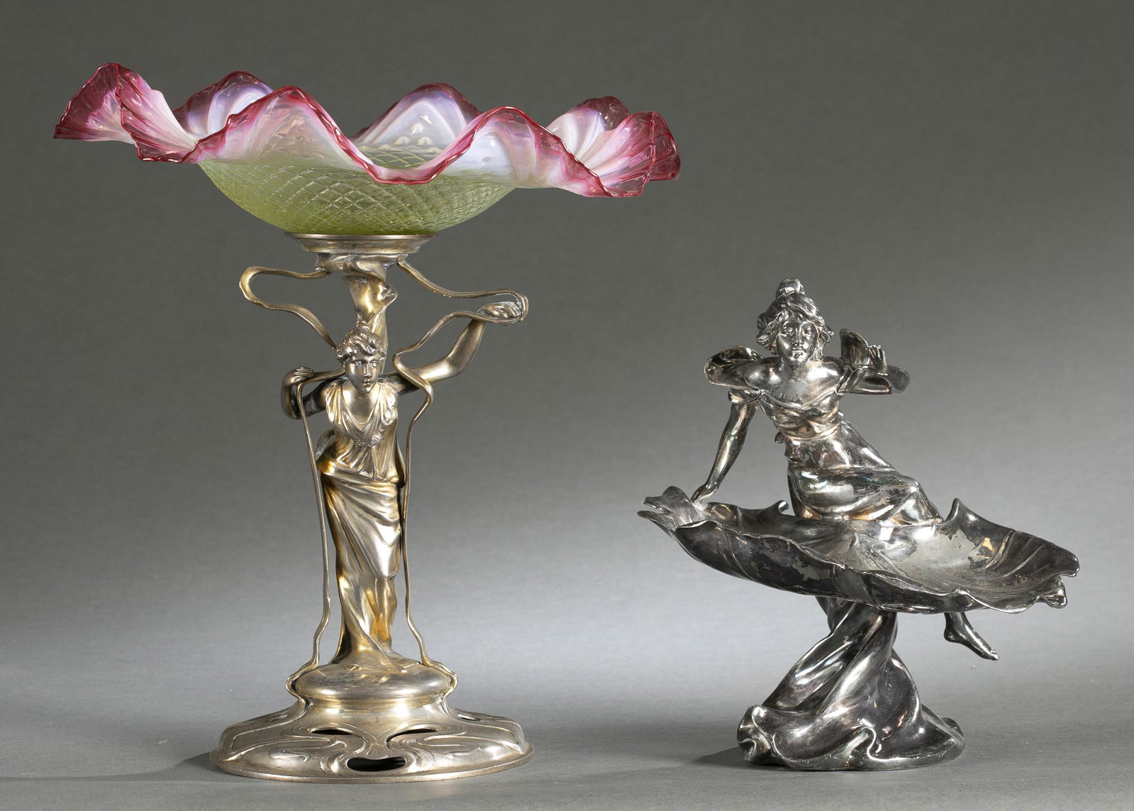 2 Art Nouveau silverplate centerpieces.: A group of two Jugendstil Art Nouveau silverplate centerpieces. ++ Centerpiece with standing woman surrounded by ribbon supports and cranberry ruffle glass bowl. 14 1/4" x 12" x 7" ++ Centerpiece with