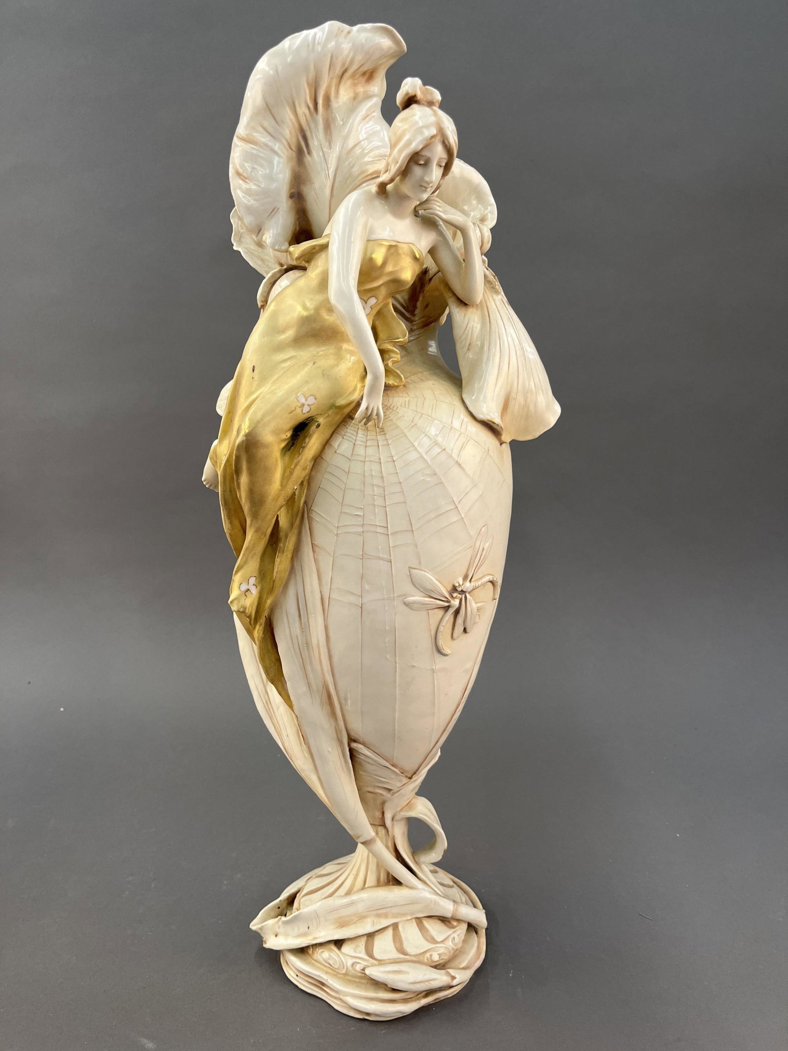 Austrian amphora.: A large sculptural amphora with a woman in a gold draped gown resting on the shoulder and large flowers sprouting from the rim. Stamped inside base. 23" x 8".Provenance: From Sylvia and Dr. William Re